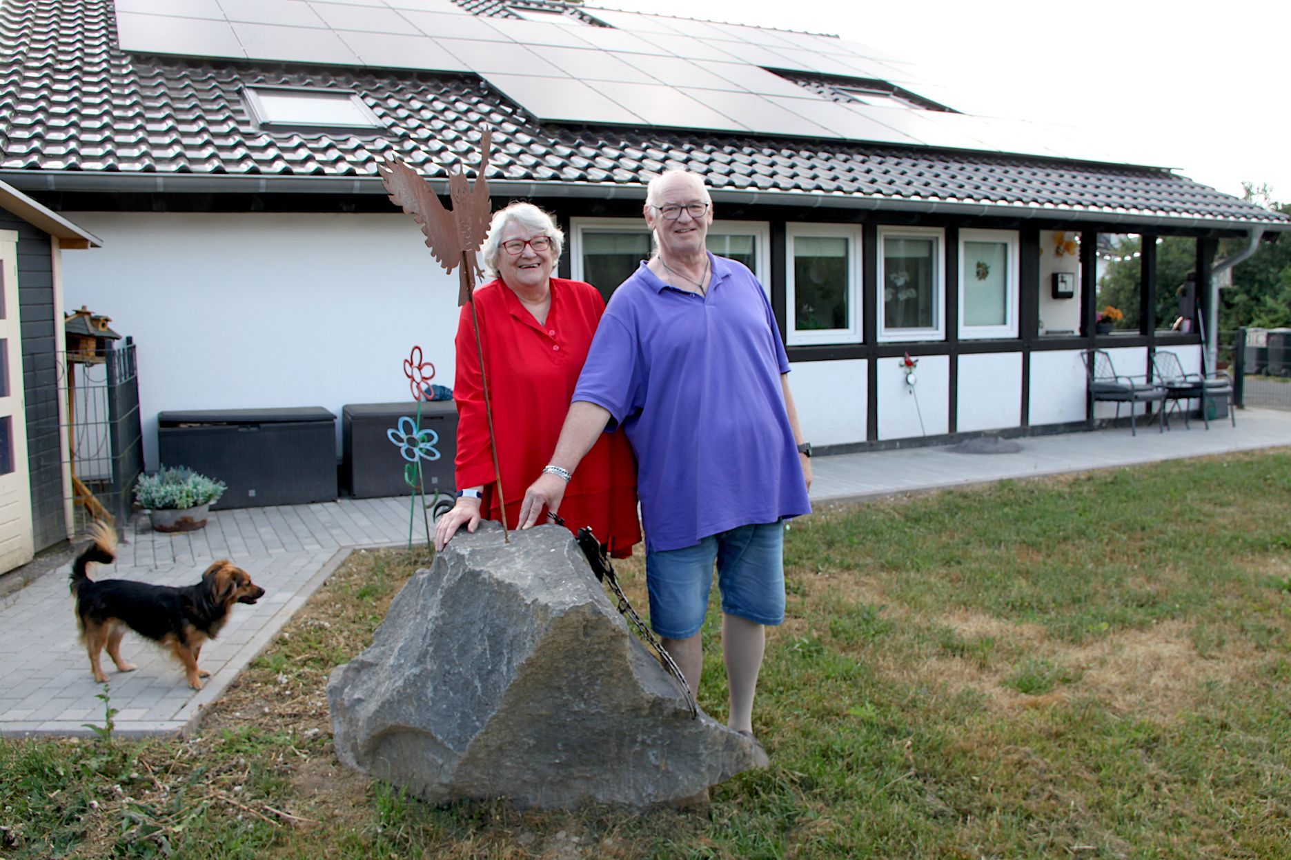 Die Eheleute Wirtz stehen mit ihrem Hund an einem großen Basaltblock. Im Hintergrund ist das neu errichtete Haus zu sehen.