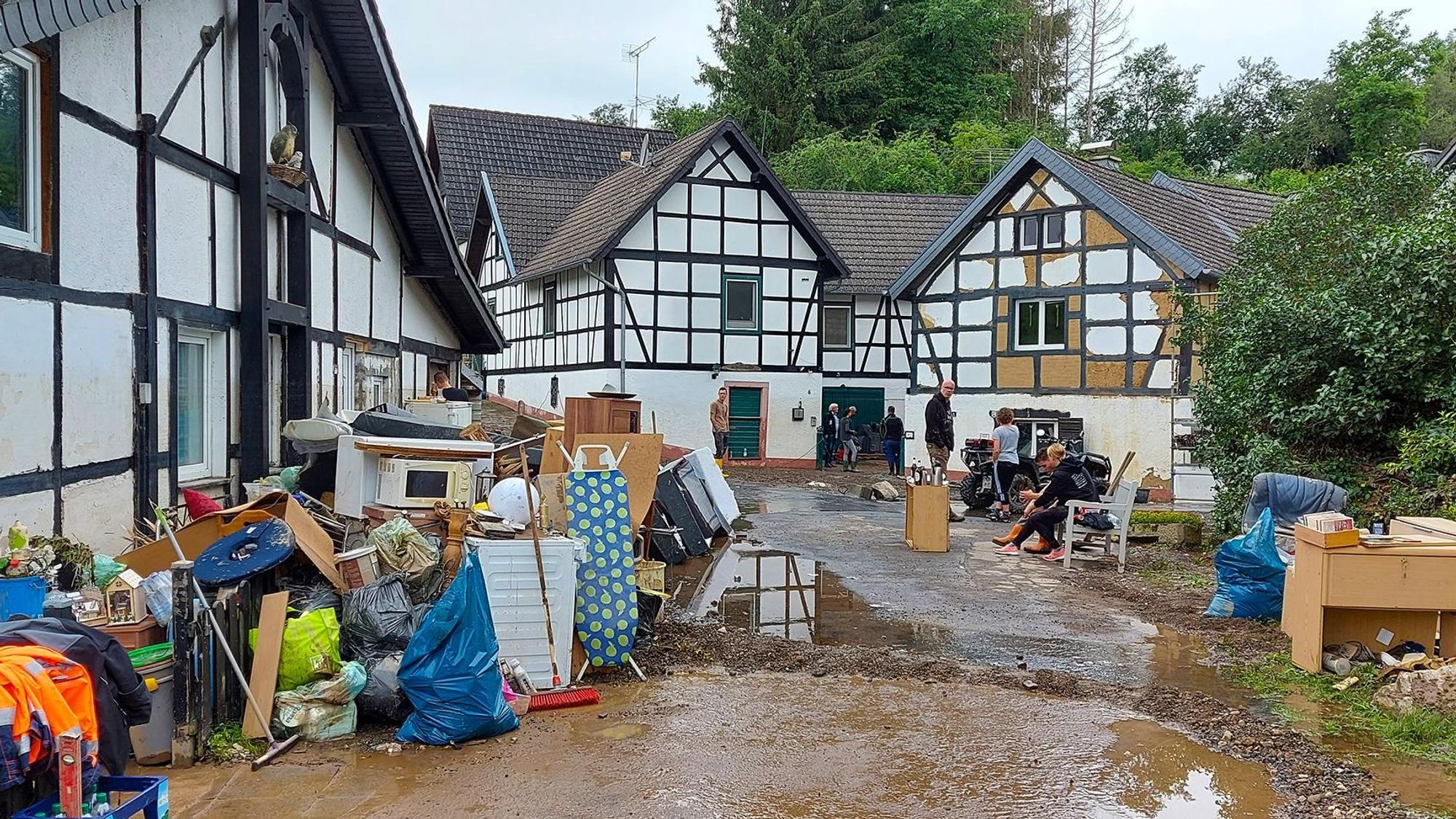 Blick auf eine Straße in Ahrdorf kurz nach Flut. Auf der Straße steht noch schlammiges Wasser. Die Anwohner haben ihr zerstörtes Mobiliar nach draußen geräumt.