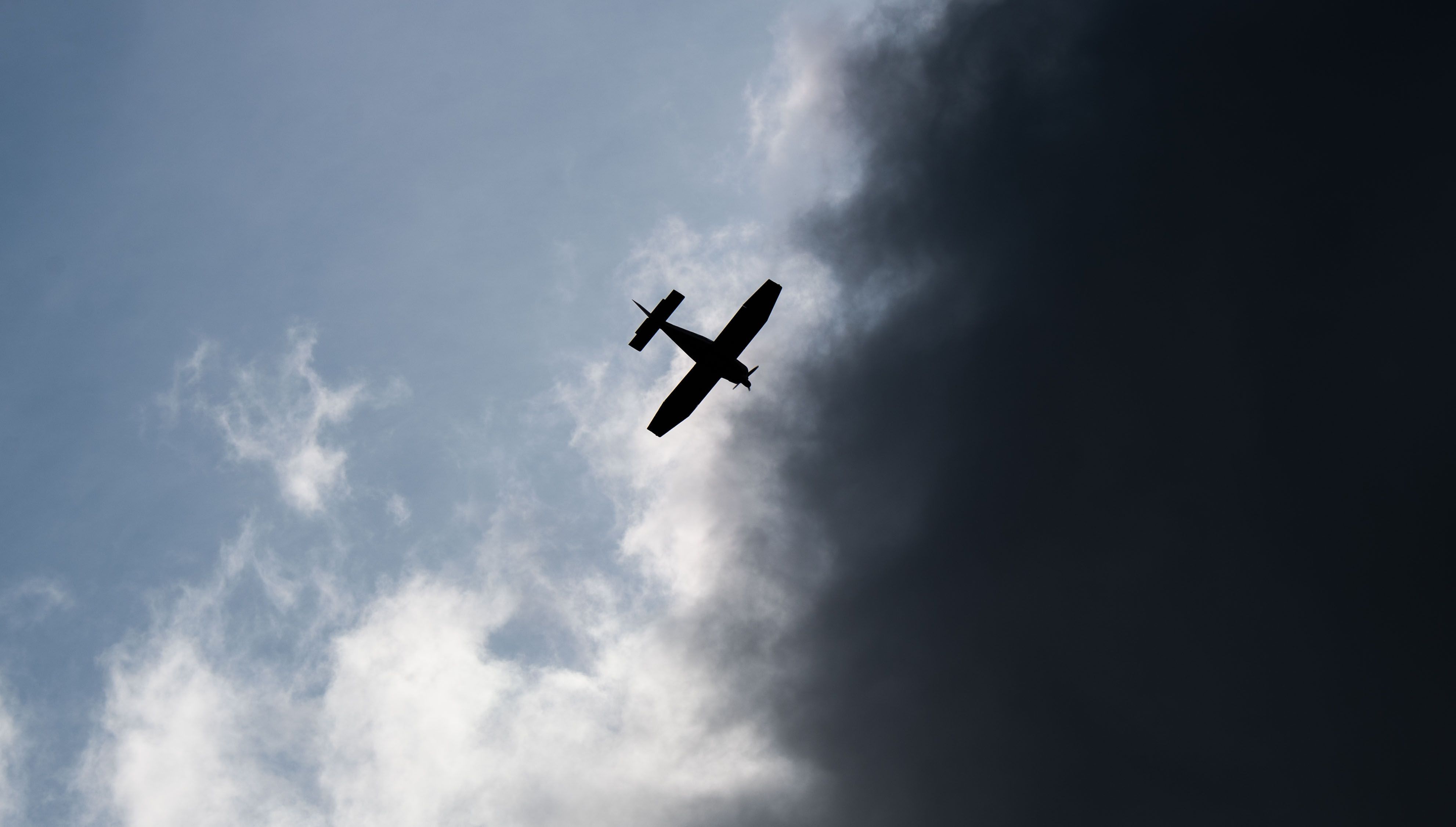 Ein Kleinflugzeug fliegt vor dunklen Wolken