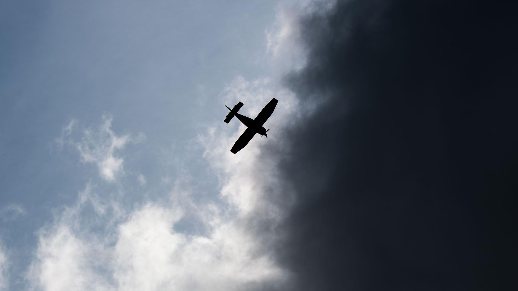 Ein Kleinflugzeug fliegt vor dunklen Wolken