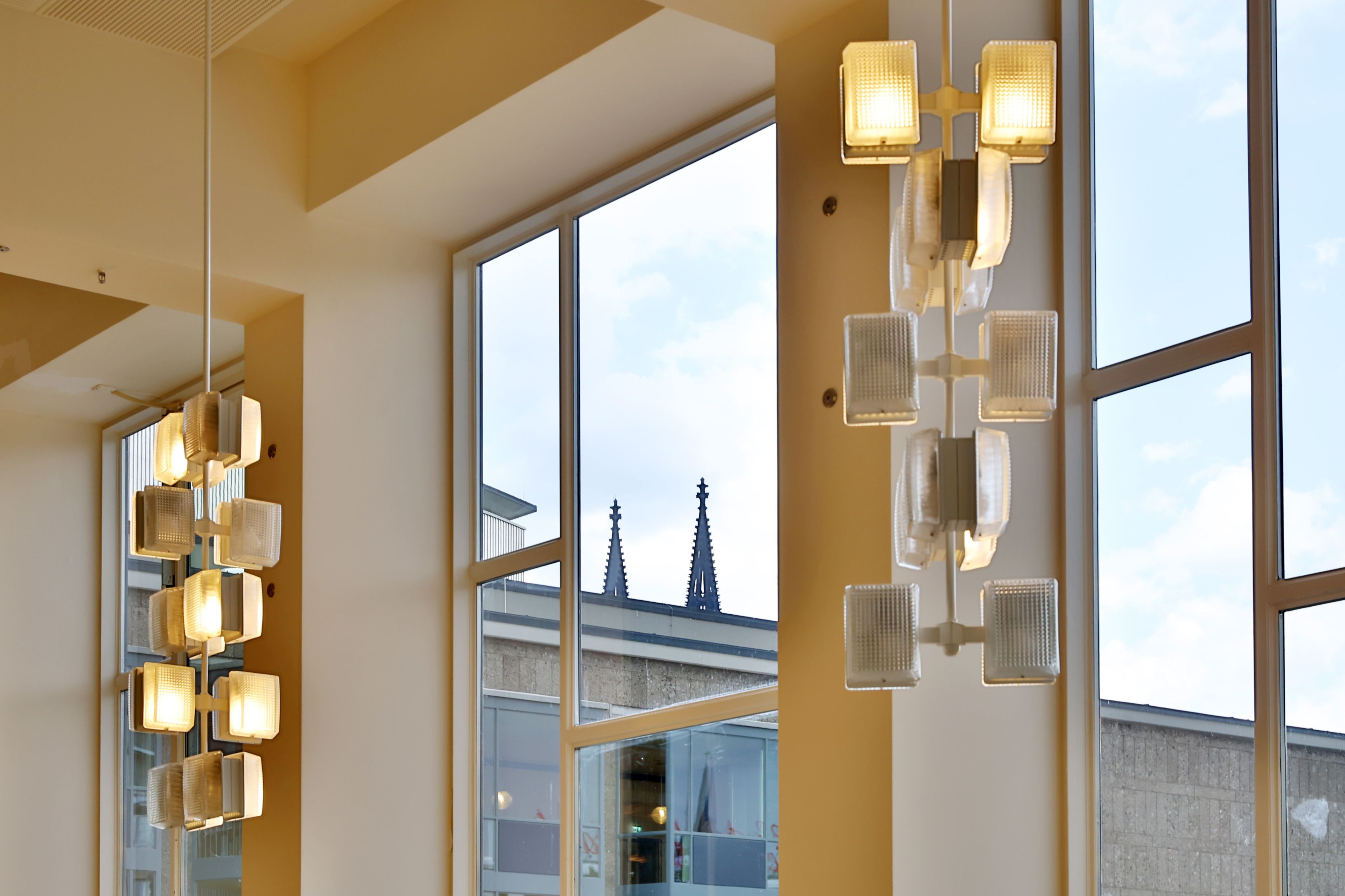 Durch ein Fenster sind die Turmspitzen einer Kirche zu erkennen.