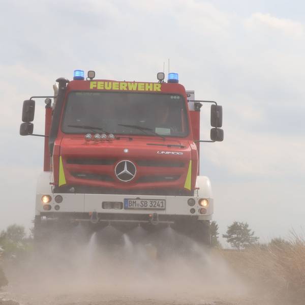 Das Bild zeigt einen Unimog der Feuerwehr Brühl mit eingeschalteten Wasserdüsen.