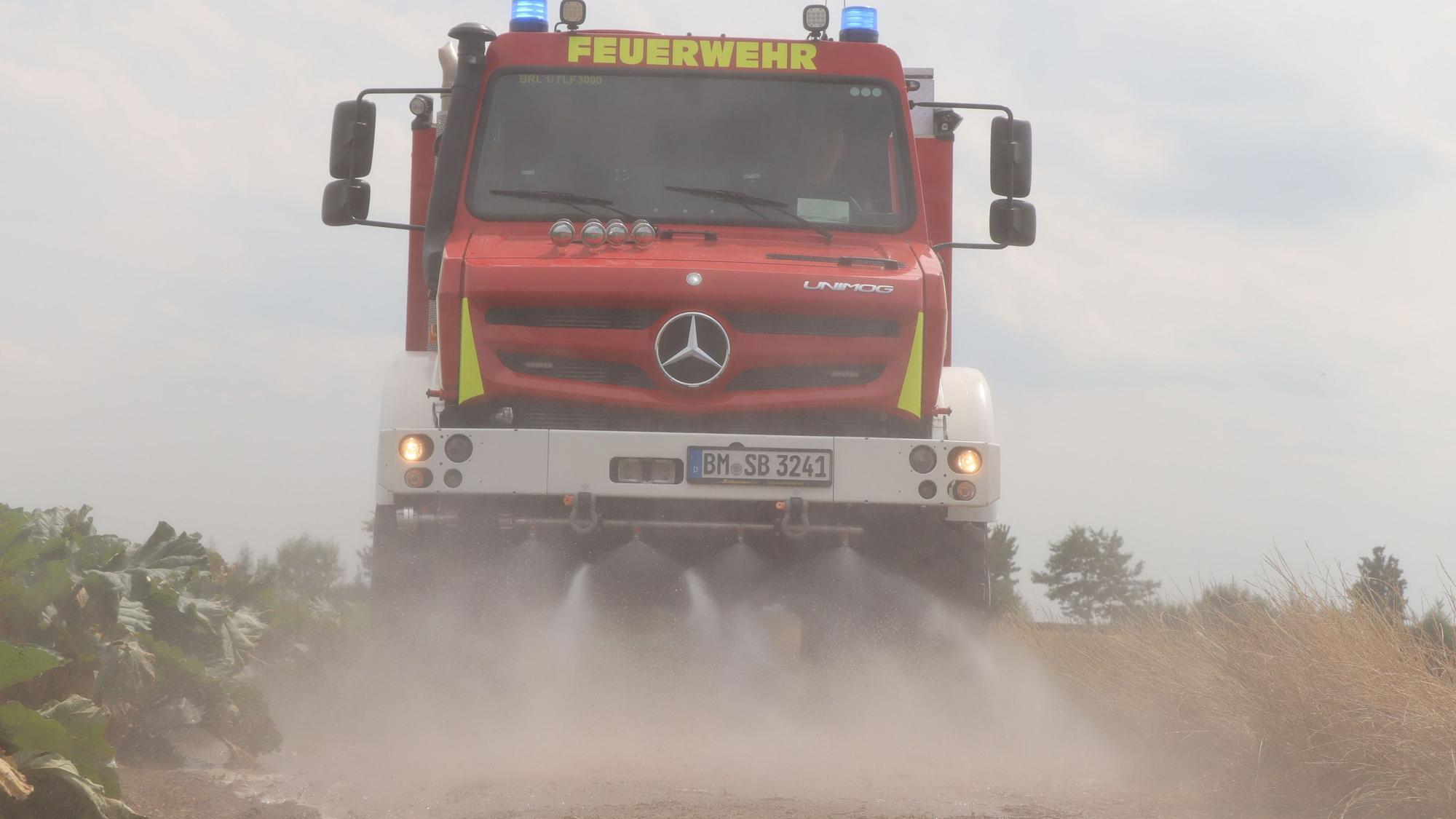 Das Bild zeigt einen Unimog der Feuerwehr Brühl mit eingeschalteten Wasserdüsen.