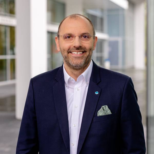 Peter Fintl trägt einen blauen Anzug und blickt lächelnd in die Kamera.