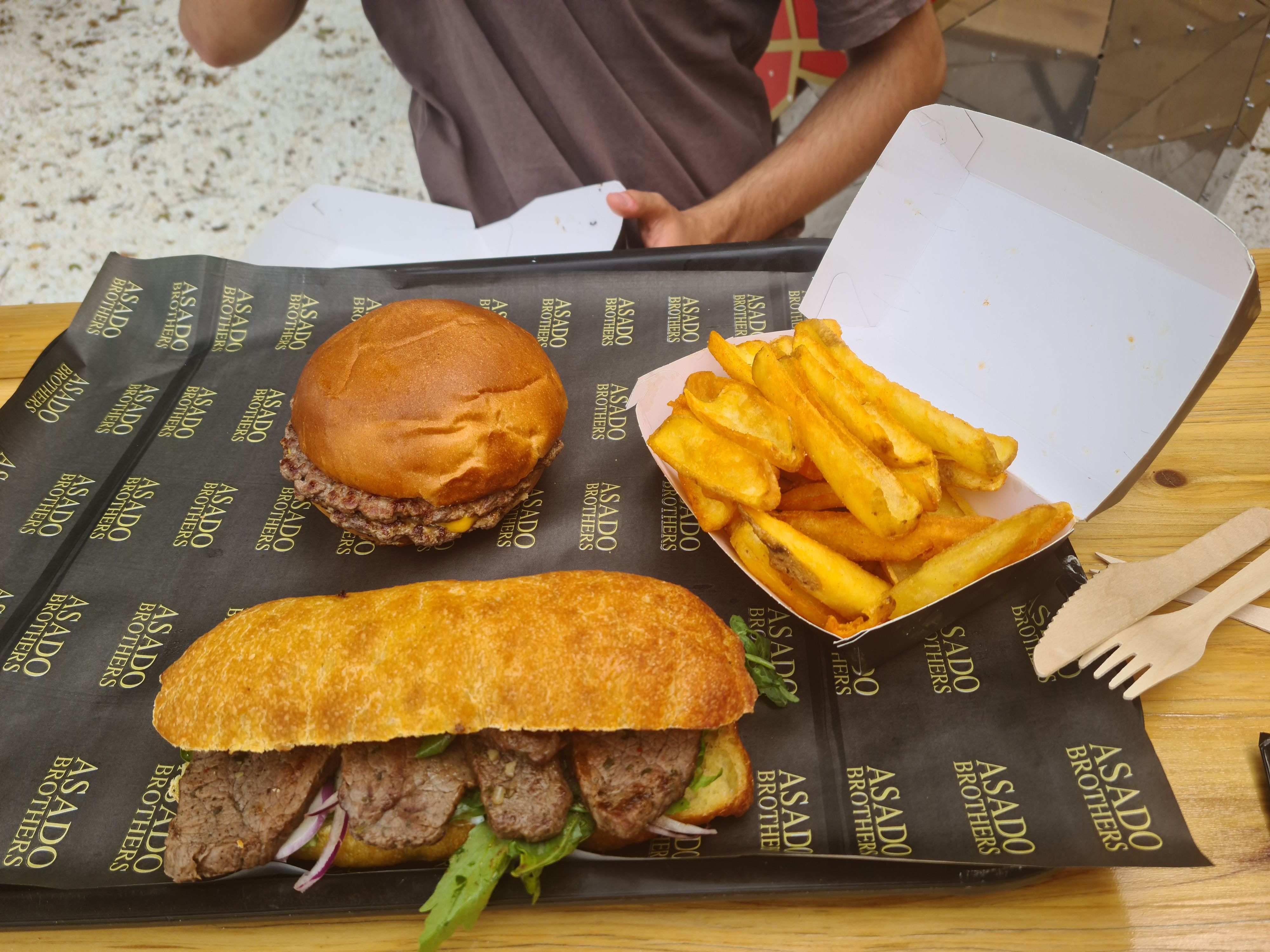 Ein Burger, ein Sandwich mit Rindfleisch und eine Portion Fritten liegen verzehrbereit auf einem Tablett.