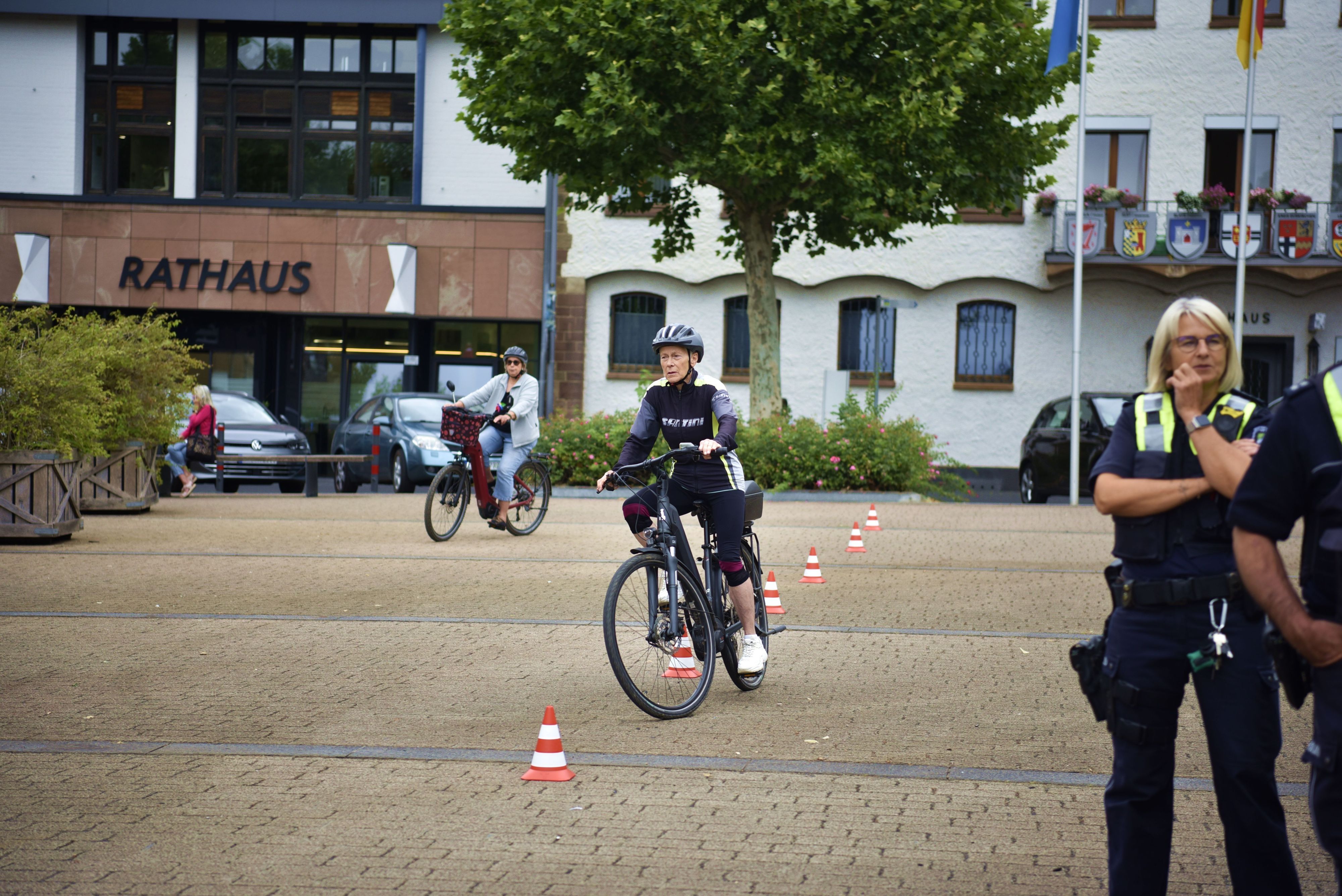 Eine Frau fährt mit einem Pedelc um rot-weiße Verkehrshütchen.