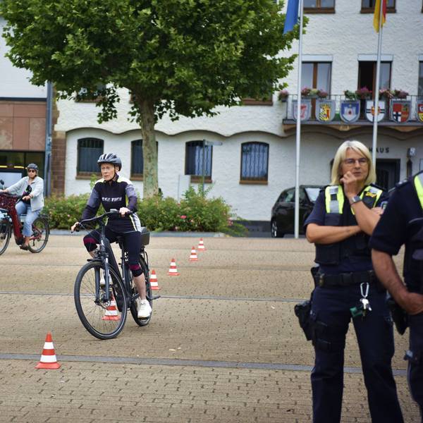 Eine Frau fährt mit einem Pedelc um rot-weiße Verkehrshütchen.