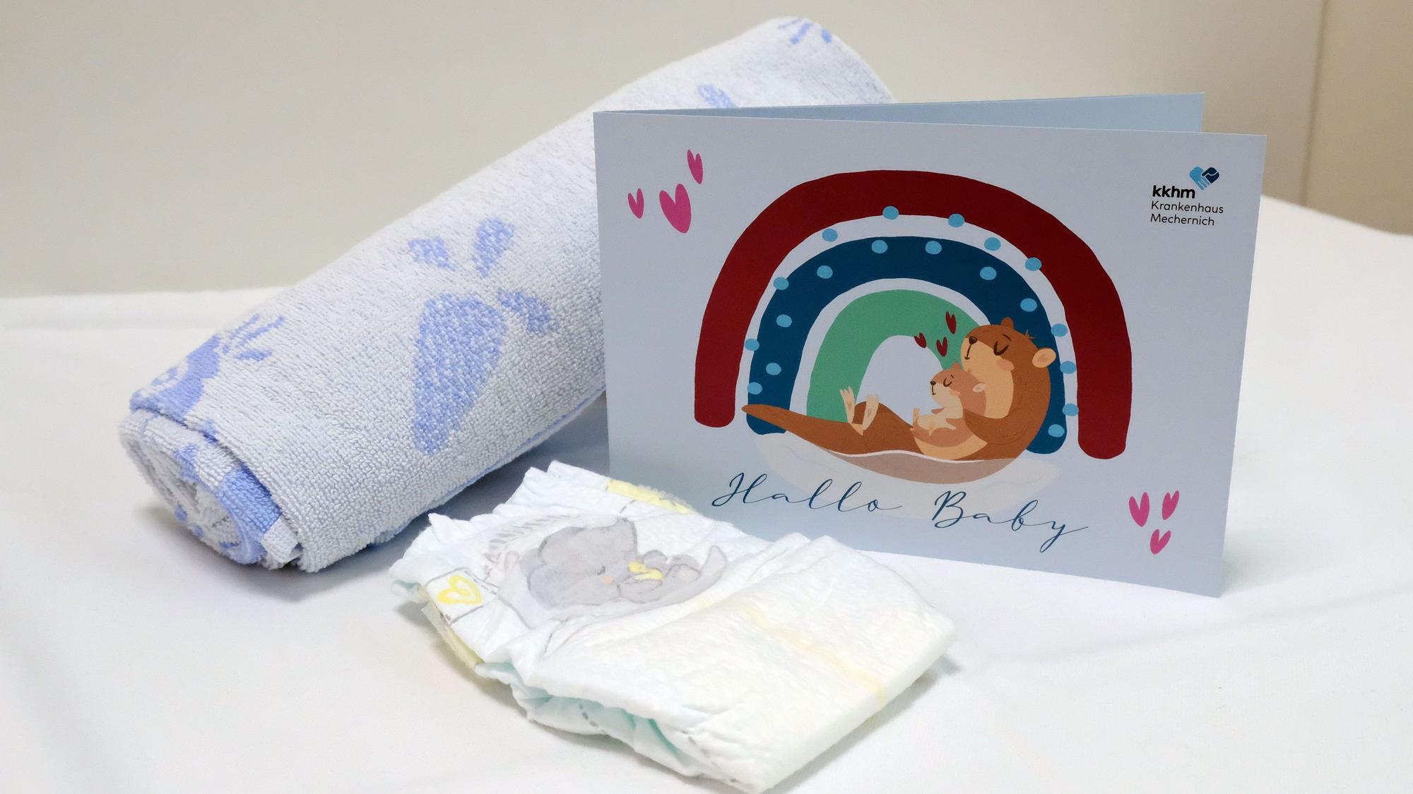 Ein zusammengerolltes Handtuch, eine Windel und eine Glückwunschkarte mit der Aufschrift „Hallo Baby“ im Mechernicher Kreißsaal.