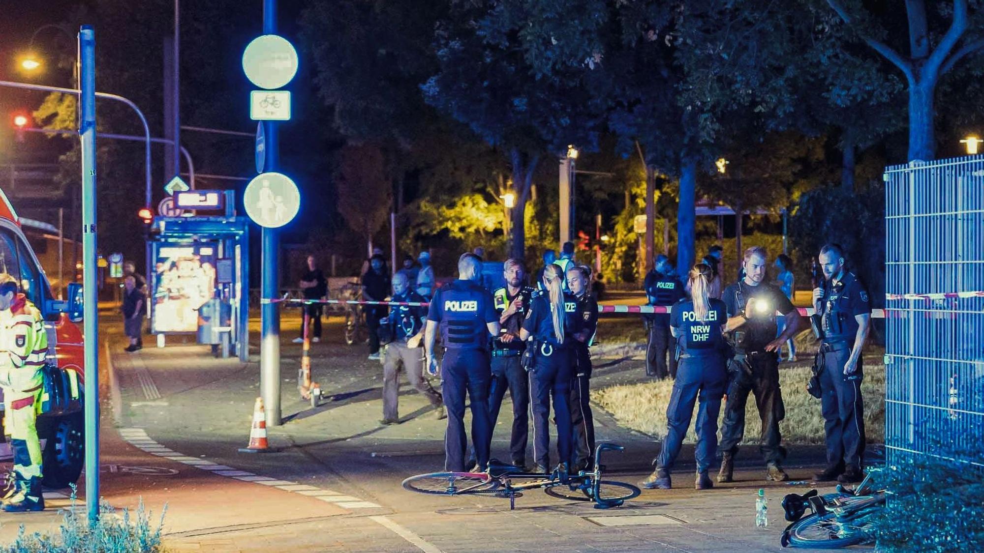 Die Polizei und Rettungskräfte sind in Köln Mülheim nach Schüssen auf offener Straße an einem Tatort beschäftigt.