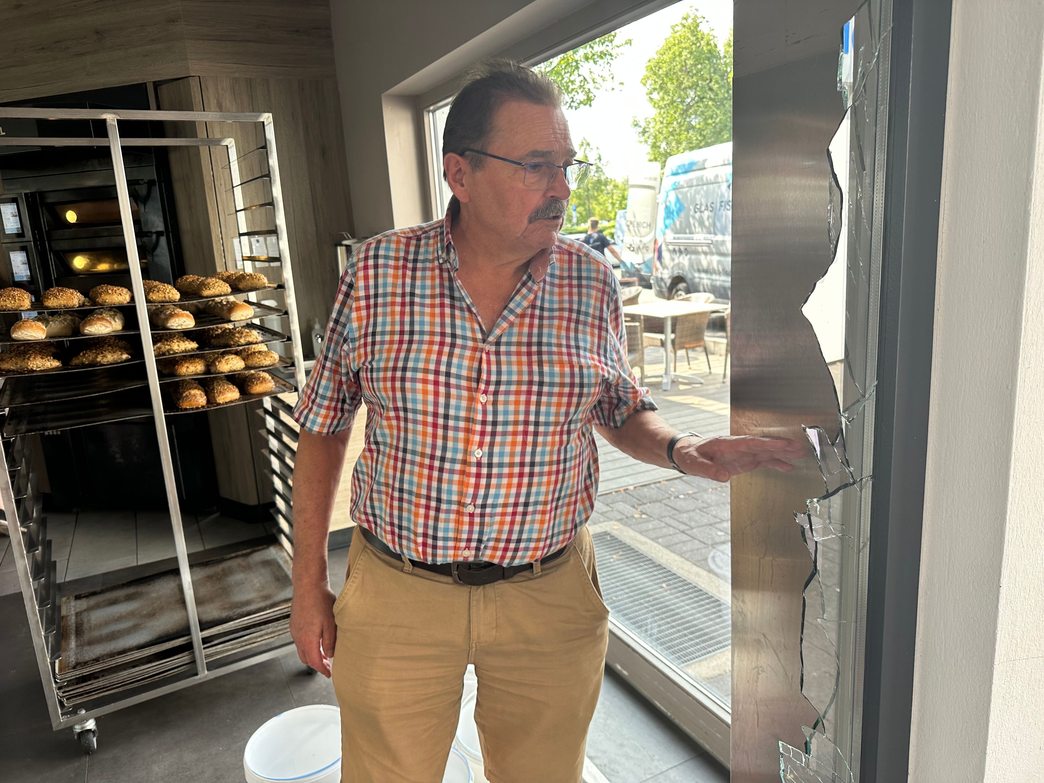 Bäckermeister Franz-Josef Gilgen an einer zerbrochenen Fensterscheibe seiner Filiale in Hennef-Uckerath.