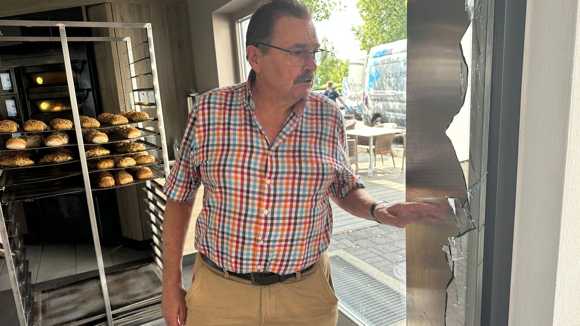 Bäckermeister Franz-Josef Gilgen an einer zerbrochenen Fensterscheibe seiner Filiale in Hennef-Uckerath.