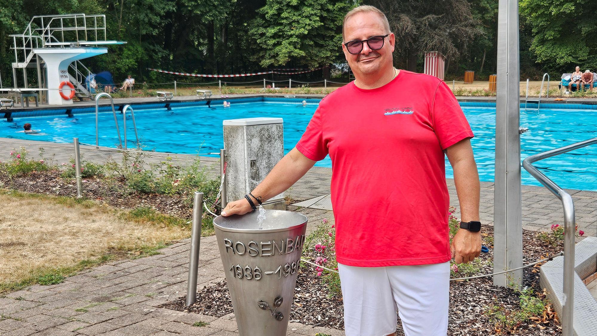 Der Badleiter mit einem roten T-Shirt und einer weißen kurzen Hose steht an einem Wasserspeier im Schwimmbad.