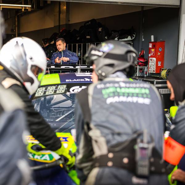 Tobias Müller steht hinter seinem Auto in der Box und erklärt einer verdeckten Person etwas.