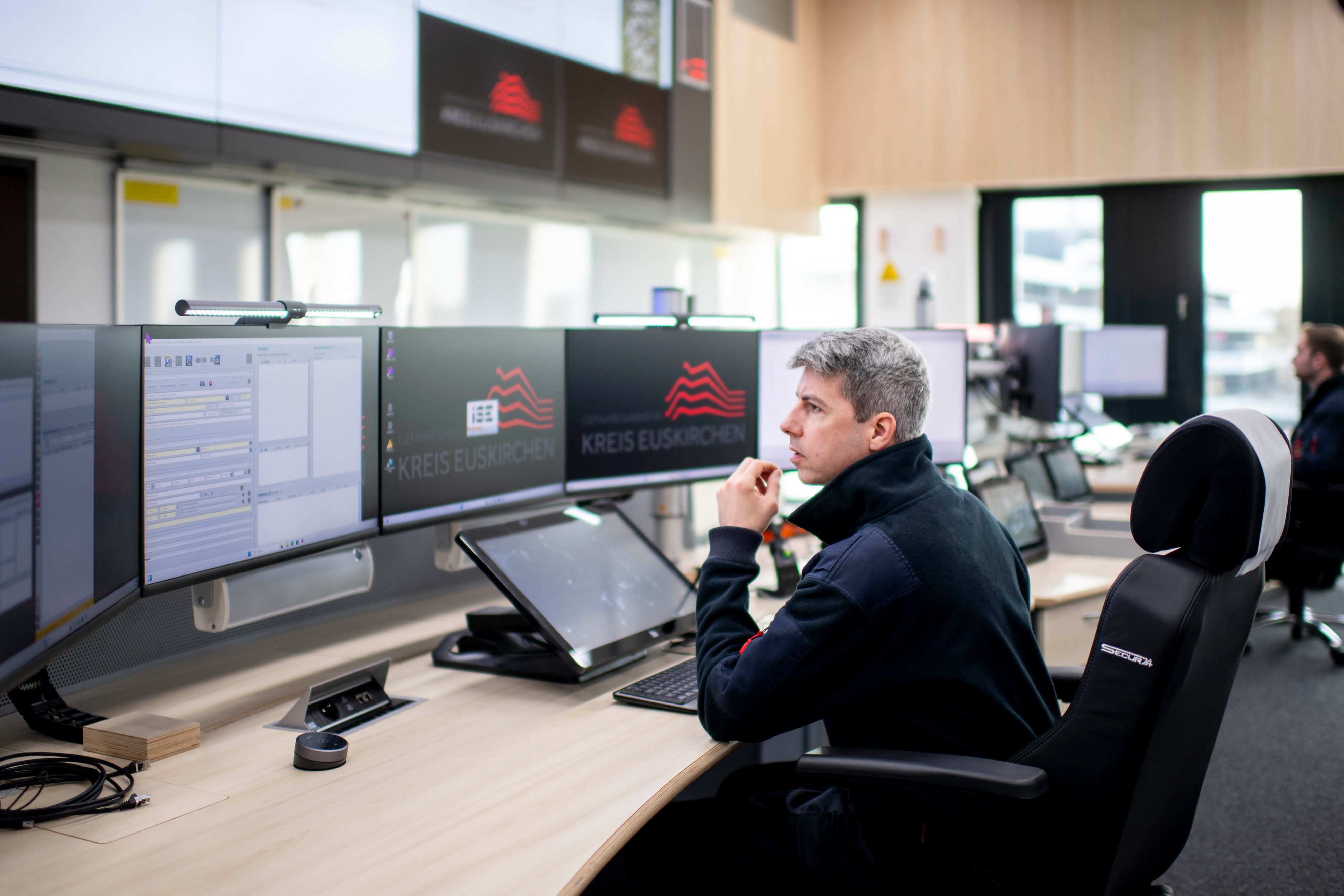 Das Bild zeigt einen Leitstellen-Disponenten hinter seinen Monitoren in der Leitstelle.