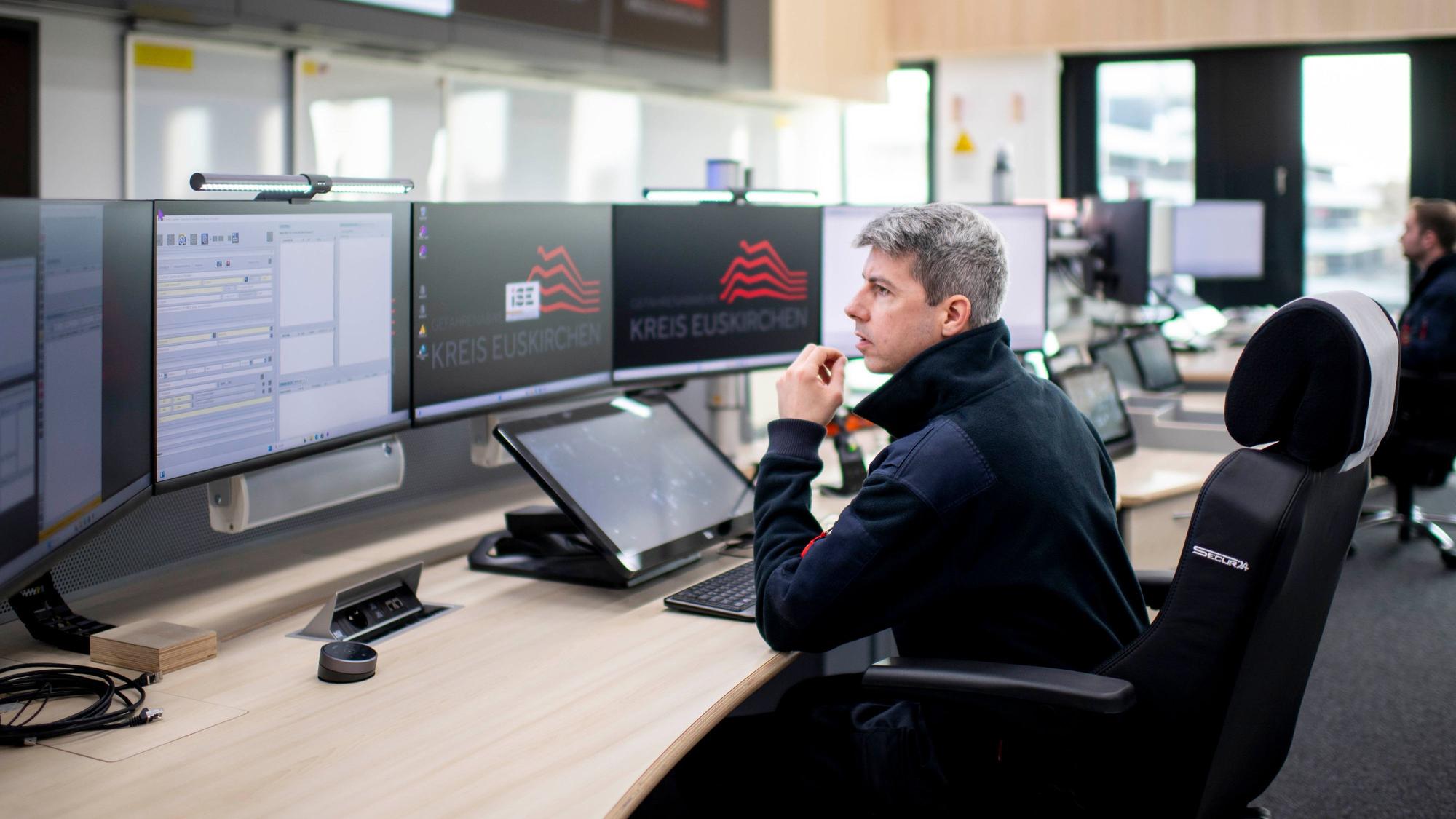 Das Bild zeigt einen Leitstellen-Disponenten hinter seinen Monitoren in der Leitstelle.