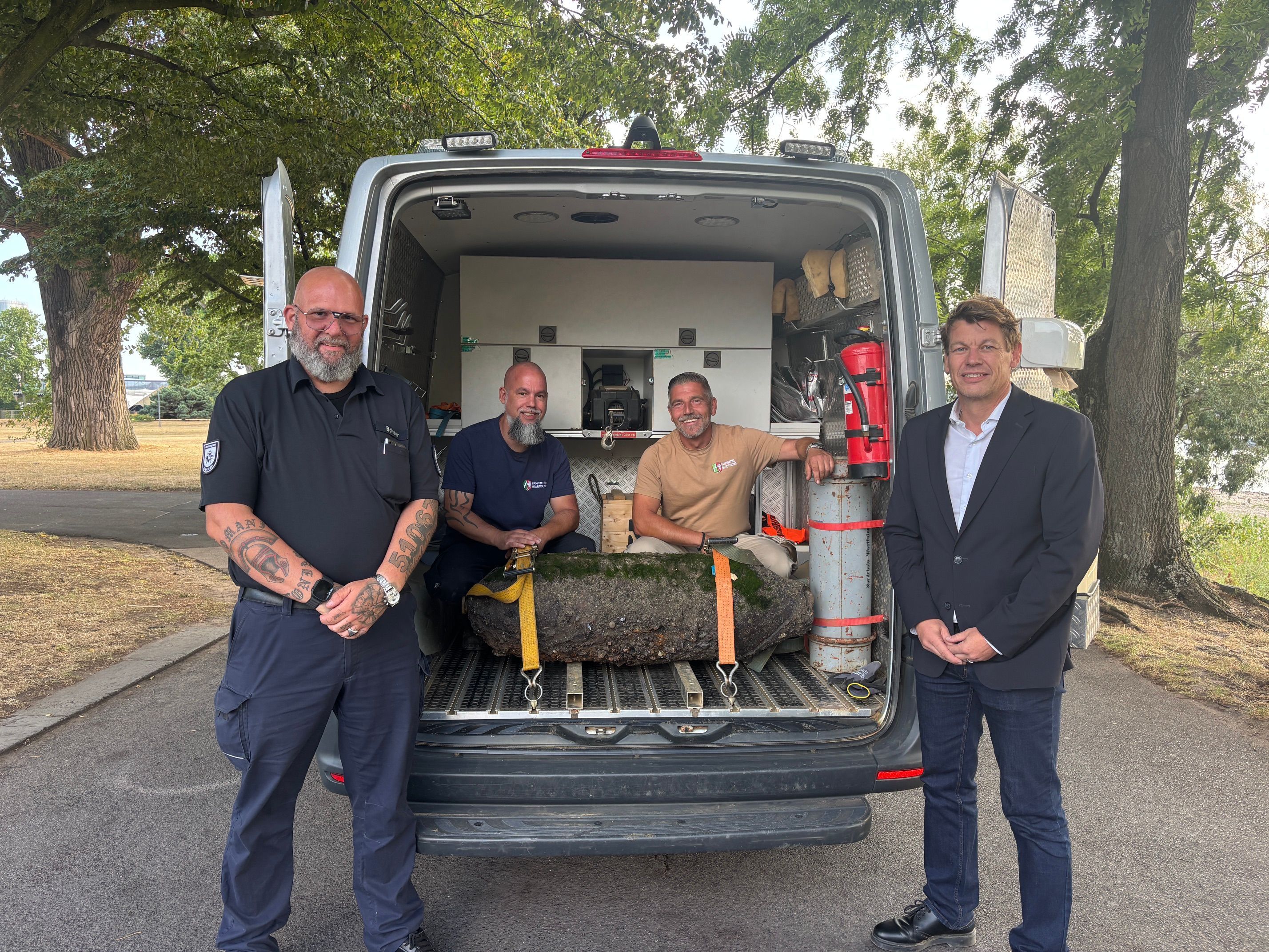 Marco Böhner (Einsatzleiter Ordnungsamt), Christoph Wassenberg und Marcel Biewald (Kampfmittelbeseitigungsdienst Rheinland der Bezirksregierung Düsseldorf) und Dirk Käsbach (Leiter des Ordnungsamtes der Stadt Köln) mit der entschärften Bombe.