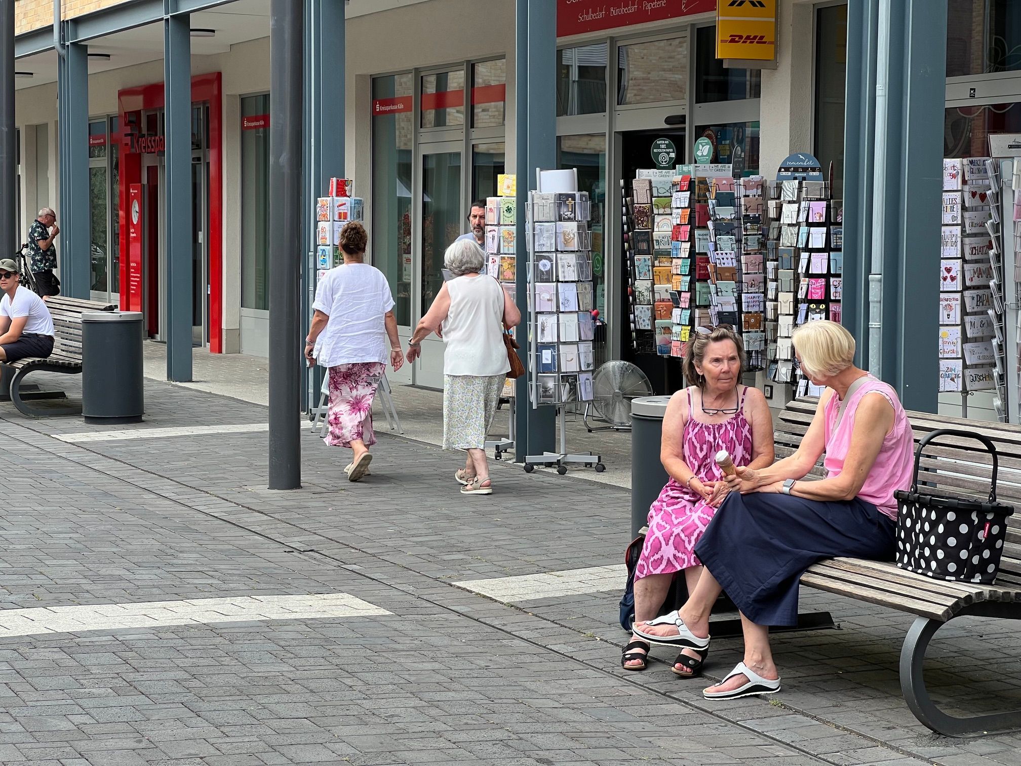Zwei Frauen sitzen auf einer Bank, sie unterhalten sich.