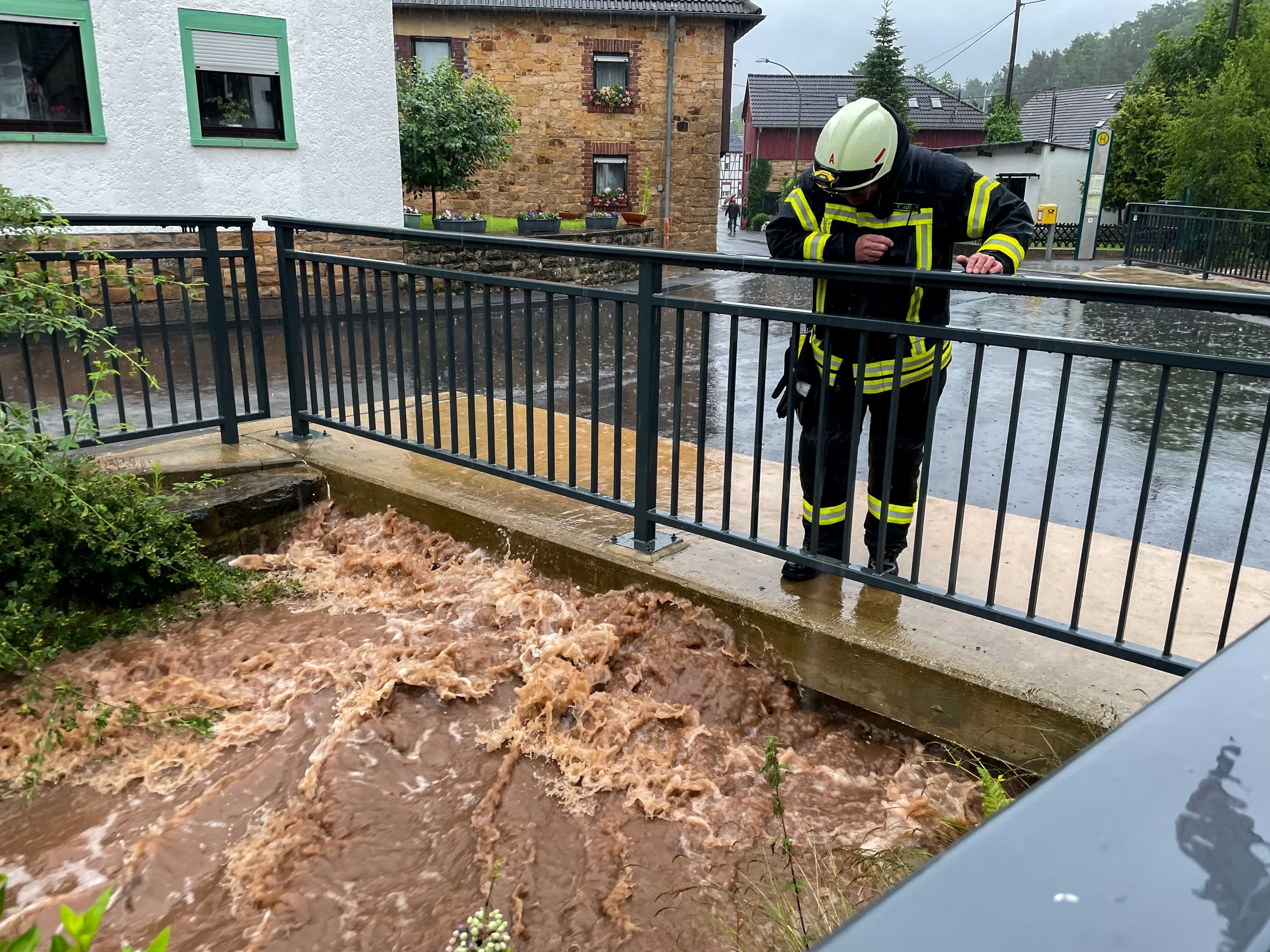 Das Bild zeigt einen Feuerwehrmann, der am 14. Juli 2021 einen Bach in Bad Münstereifel-Gilsdorf beobachtet.