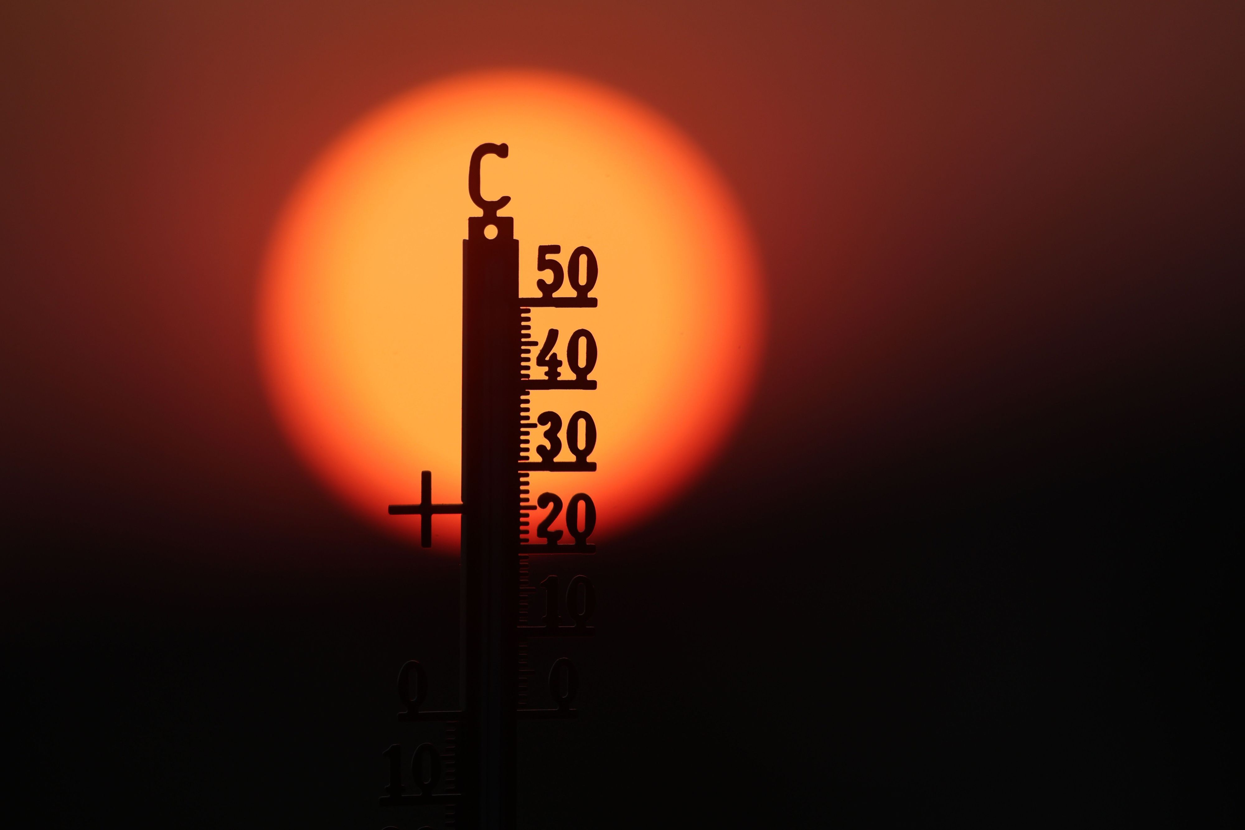 Hinter einem Thermometer geht am Morgen die Sonne auf. (Symbolbild)