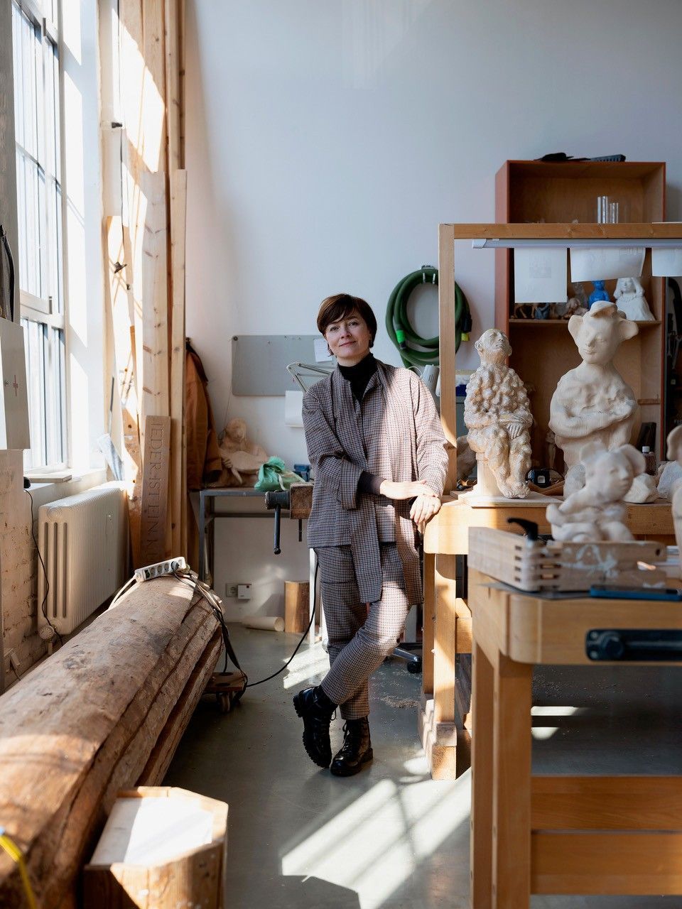 Eine Frau steht in einem Atelier, in Regalen befinden sich mehrere Skulpturen.