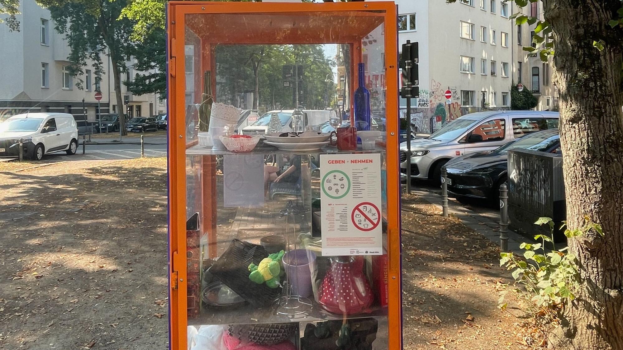 Ein Glasschrank am Eierplätzchen in der Südstadt, in dem es kostenlose Sachen gibt, mit einem Regelzettel.