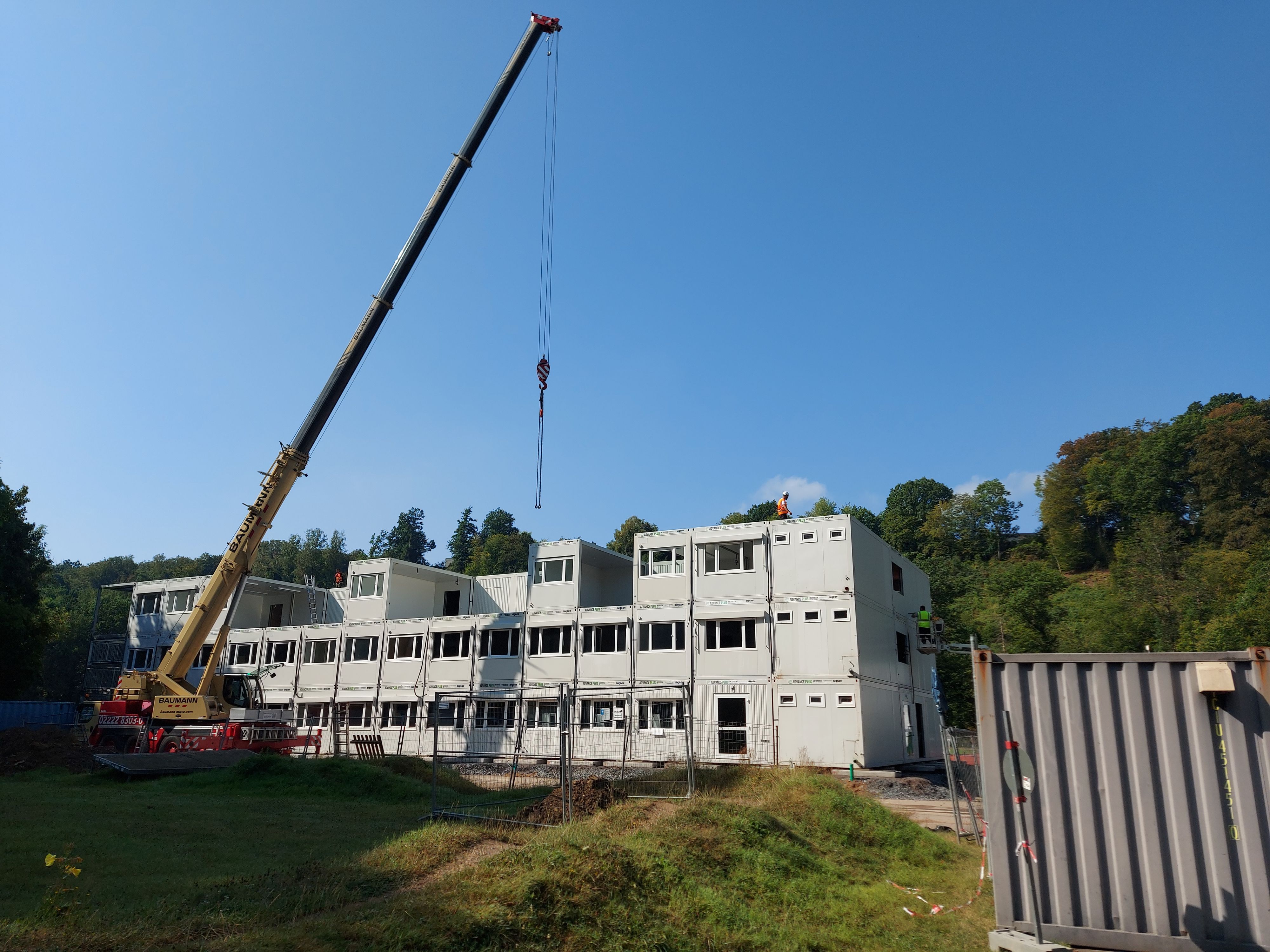 Ein Kran vor einem Containerrohbau.
