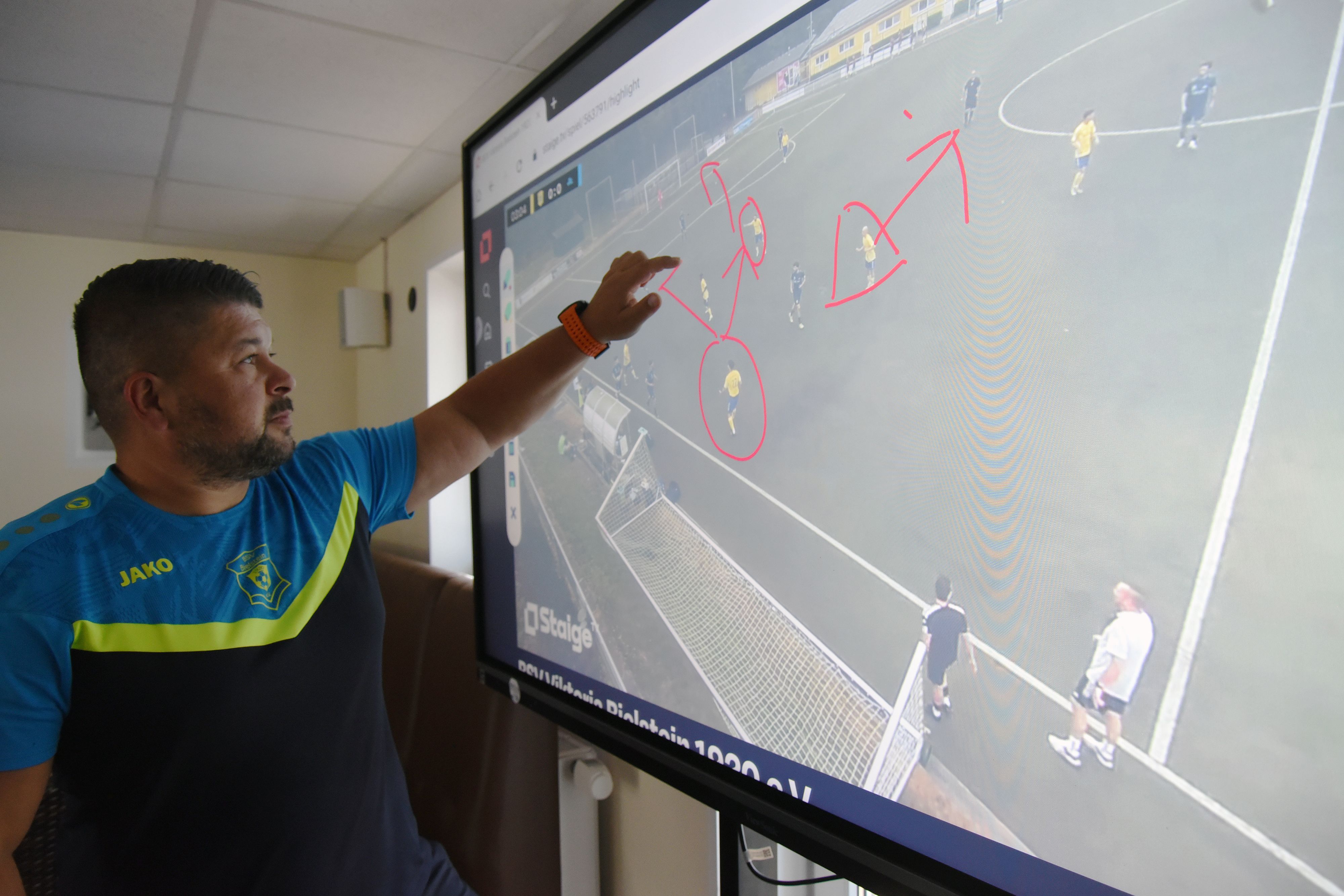 Christopher Pethe analysiert ein Fußballspiel auf einem Smartboard.