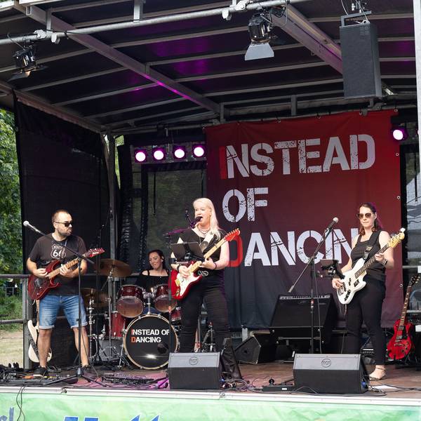 Ein Gitarrist, die Sängerin, die ebenfalls Gitarre spielt, und eine Bassistin stehen vorne auf der Bühne, im Hintergrund ist die Schlagzeugerin zu sehen.