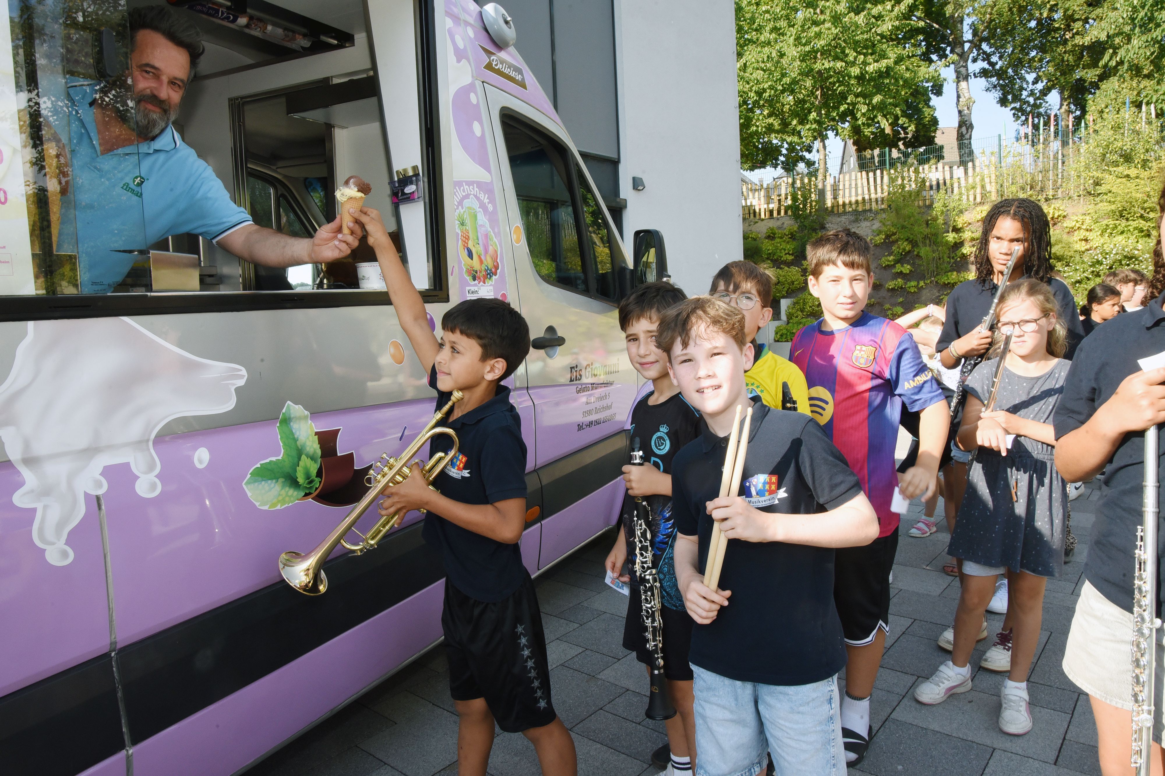 Kinder mit Musikinstrumenten stehen vor einem Eiswagen.