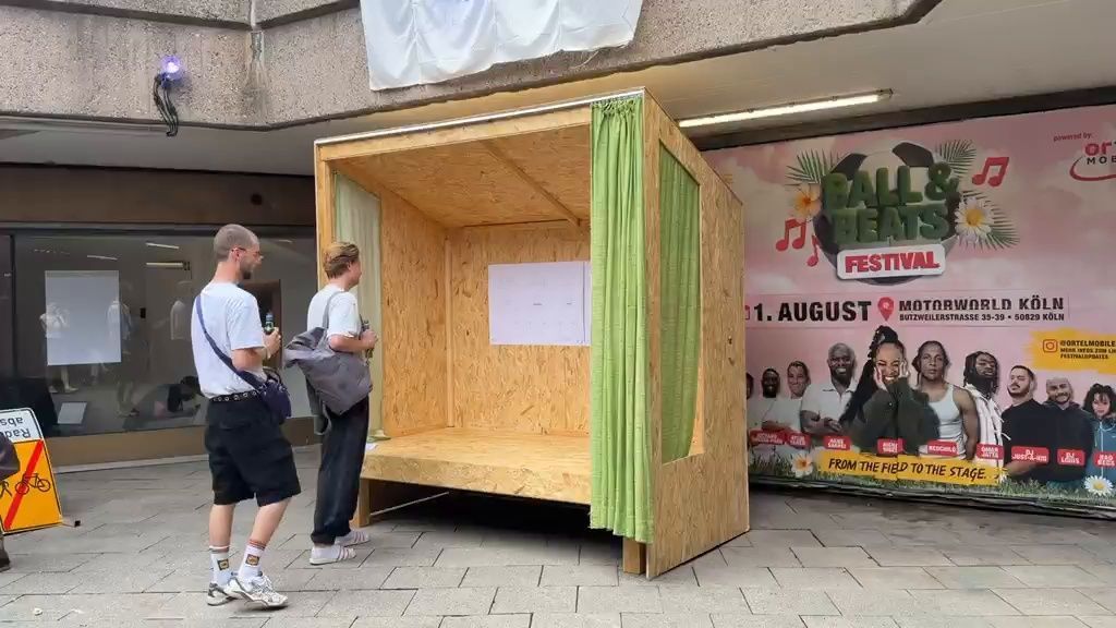 Zwei Männer stehen vor einer überdachten Holzbank.