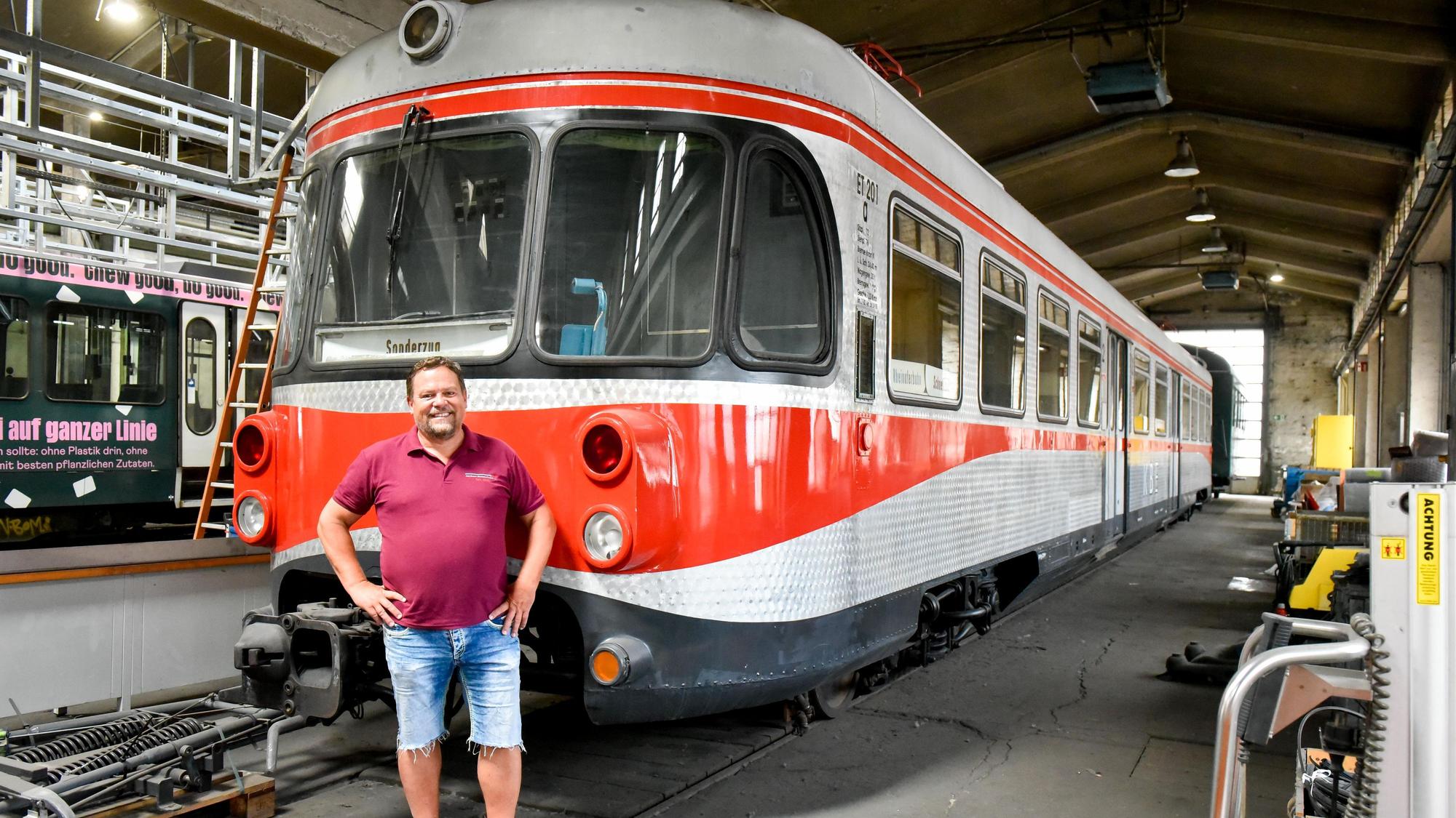 Das Foto zeigt einen Mann, der vor einer alten Bahn steht.