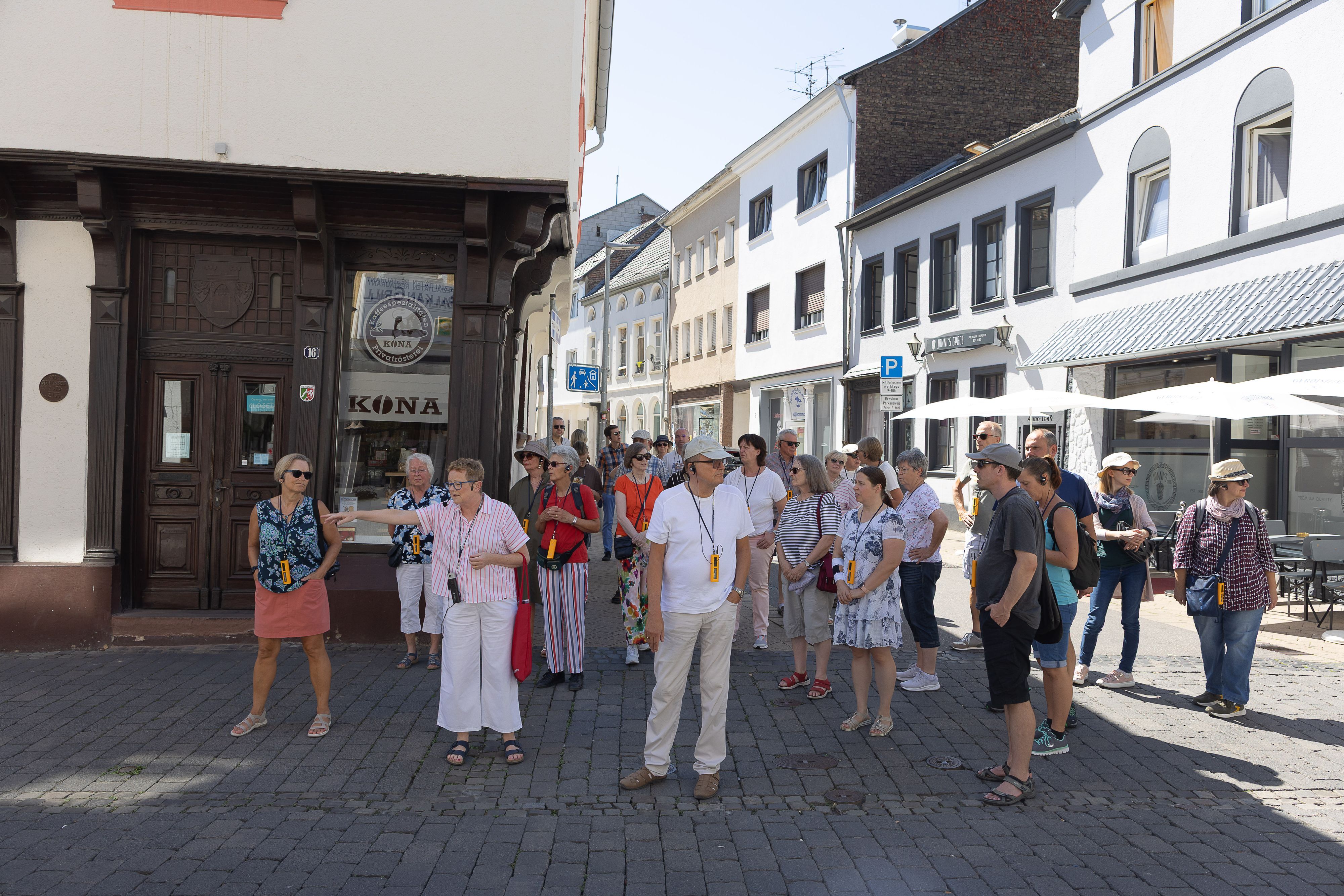 Eine Gruppe Menschen steht auf einer Straße, ringsherum sind Häuser zu sehen.
