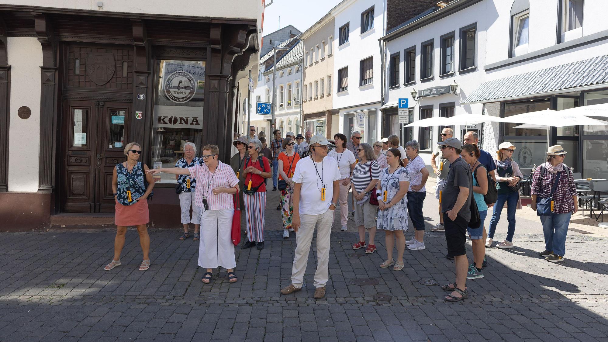 Eine Gruppe Menschen steht auf einer Straße, ringsherum sind Häuser zu sehen.