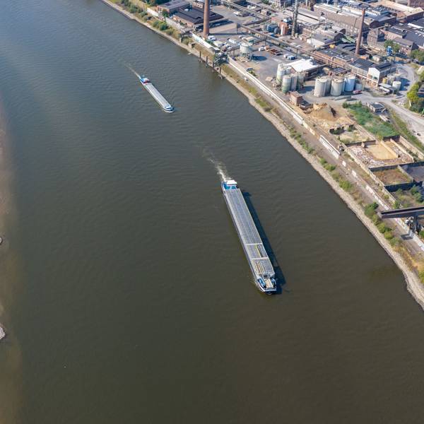 Am Rhein in Duisburg fahren Schiffe in der Fahrrinne, am Ufer sind breite Sandbänke sichtbar, die bei normalem Wasserstand unter Wasser sind.