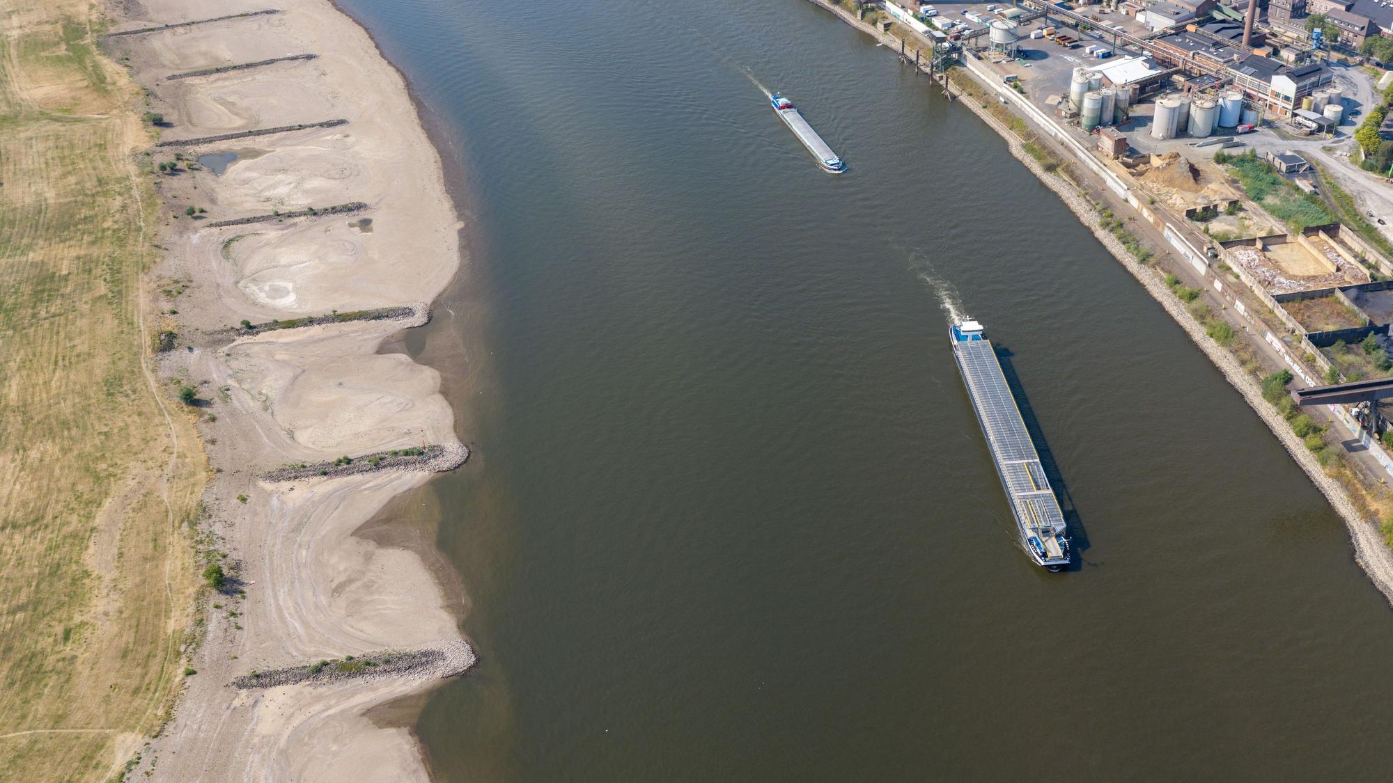 Am Rhein in Duisburg fahren Schiffe in der Fahrrinne, am Ufer sind breite Sandbänke sichtbar, die bei normalem Wasserstand unter Wasser sind.