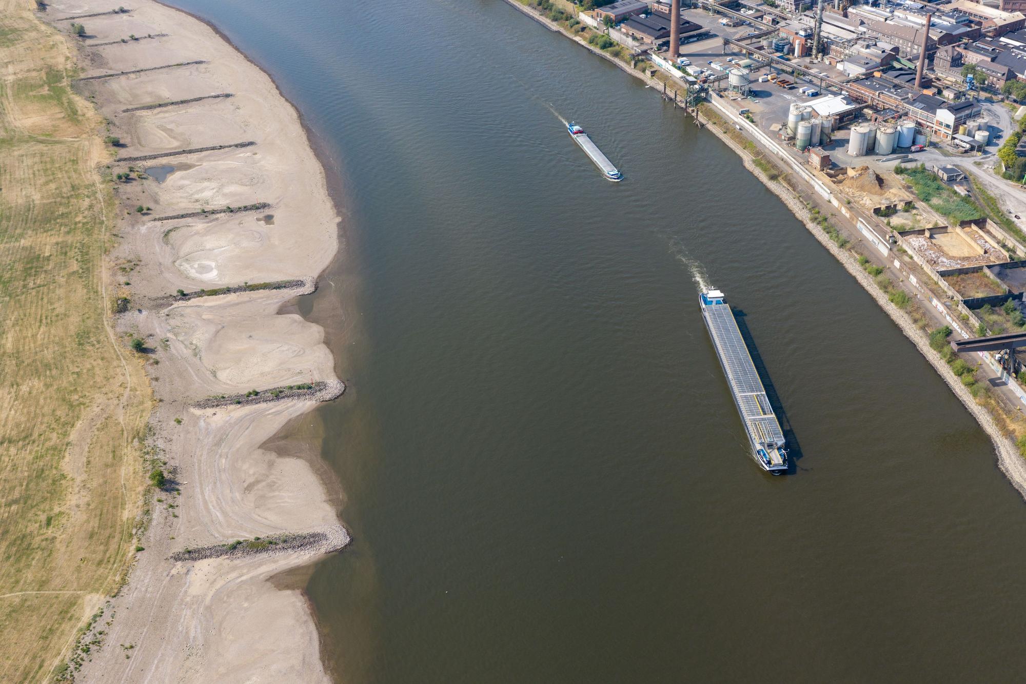 Am Rhein in Duisburg fahren Schiffe in der Fahrrinne, am Ufer sind breite Sandbänke sichtbar, die bei normalem Wasserstand unter Wasser sind.