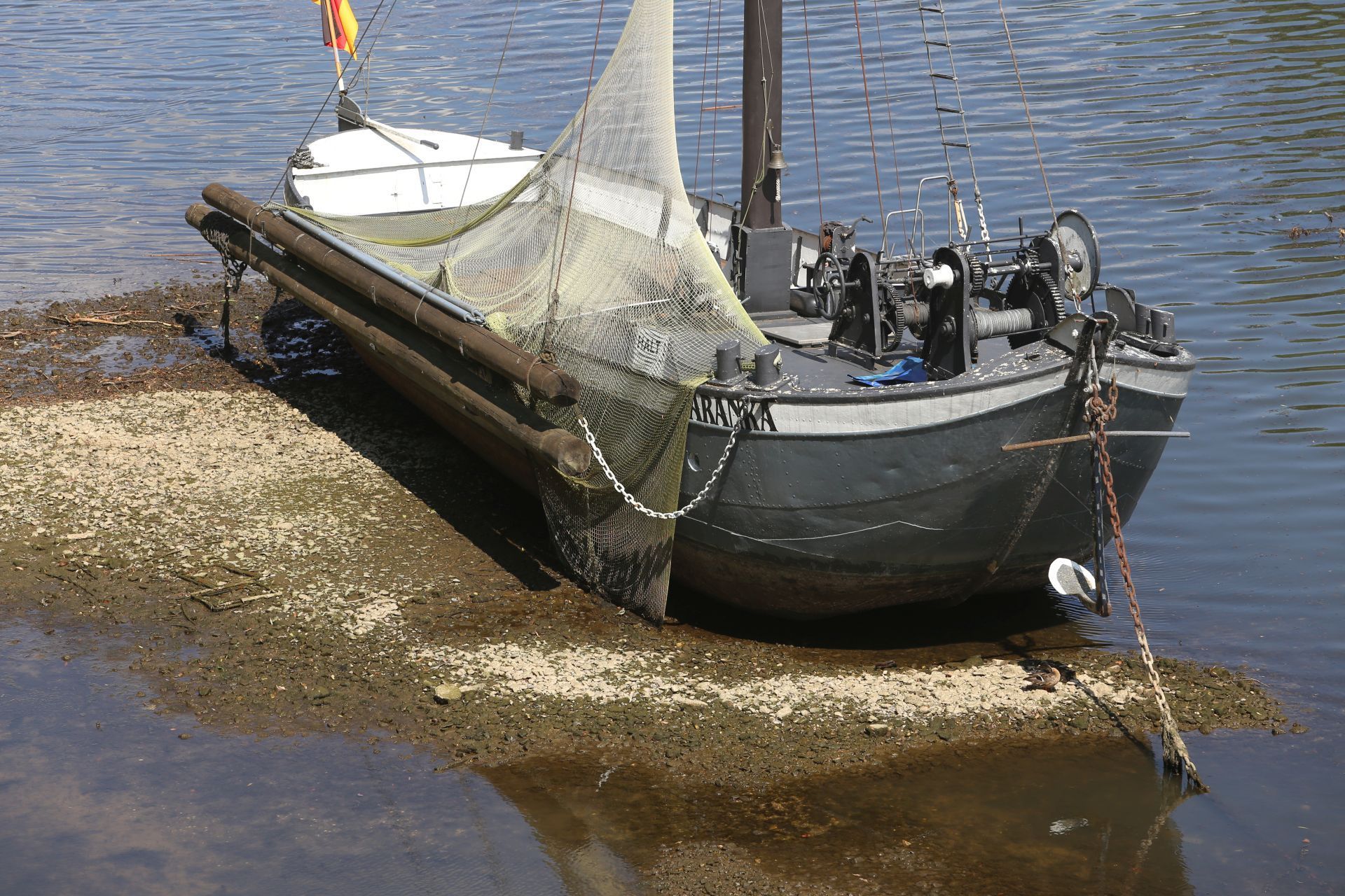 Ein historisches Schiff mit einem flachen Boden liegt auf Grund.