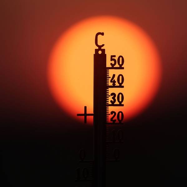 Hinter einem Thermometer geht am Morgen die Sonne auf.