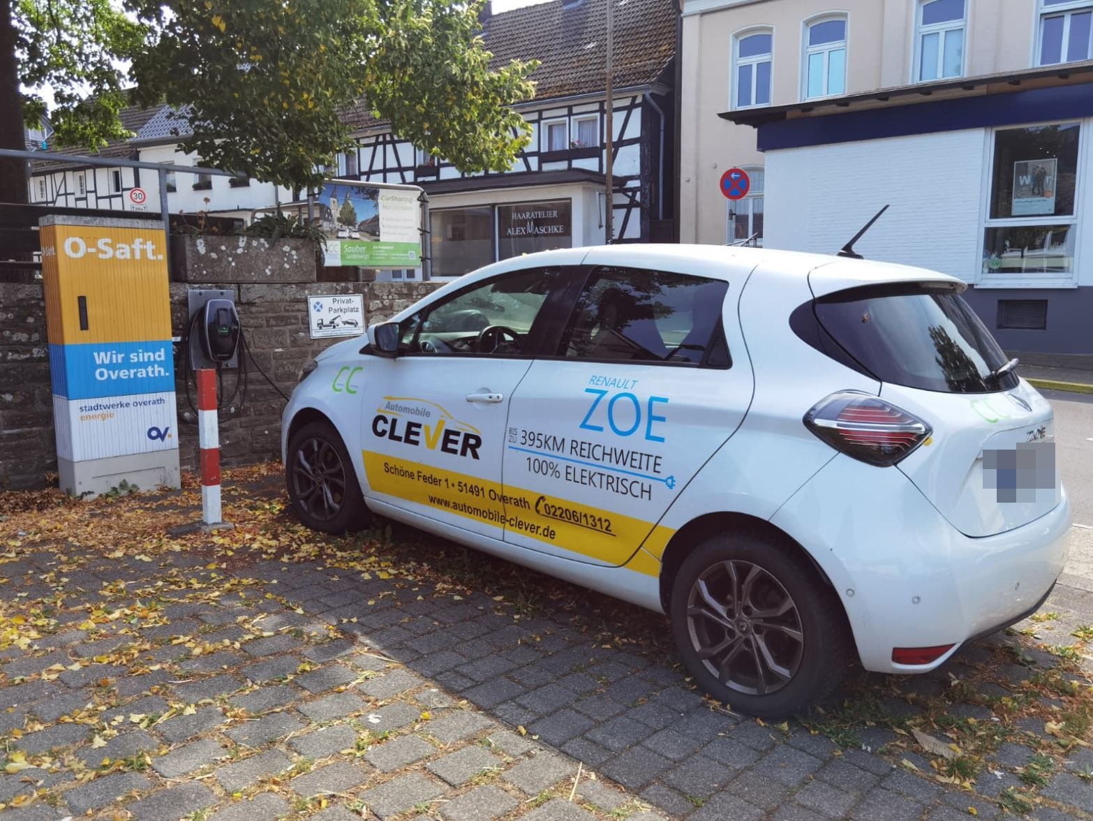 Ein E-Auto steht an einer Ladestation auf einem Parkplatz.