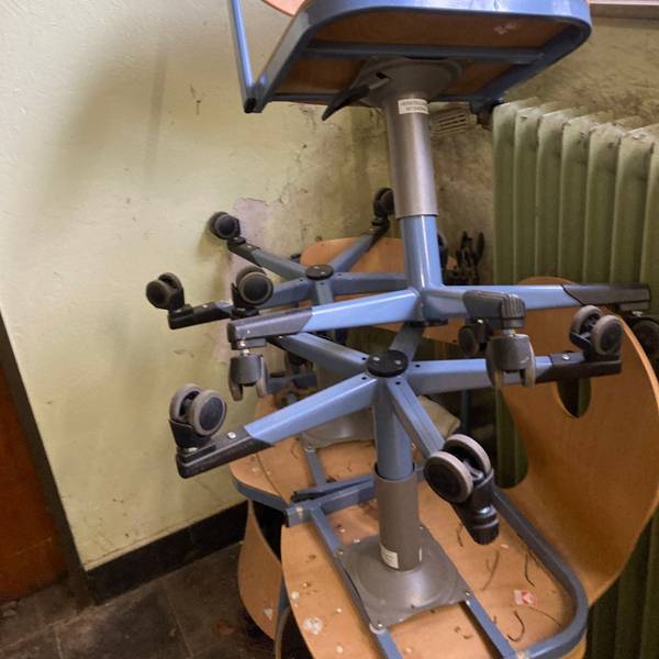 Alte Schulstühle stehen vor einer Wand mit Schimmelbefall.