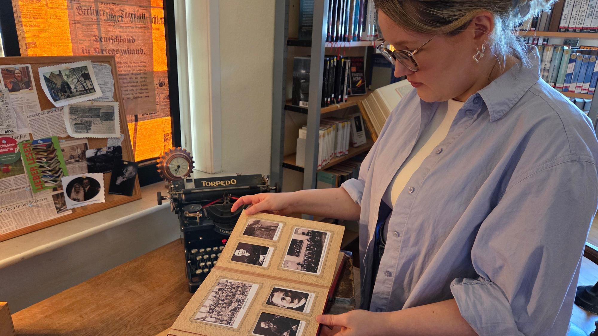 Aus dem Waldbröler Stadtarchiv stammen historische Fotografien, die Hinweise bergen können. Carolin Peters aus dem Leitungsteam der Stadtbücherei blättert in einem der Alben.