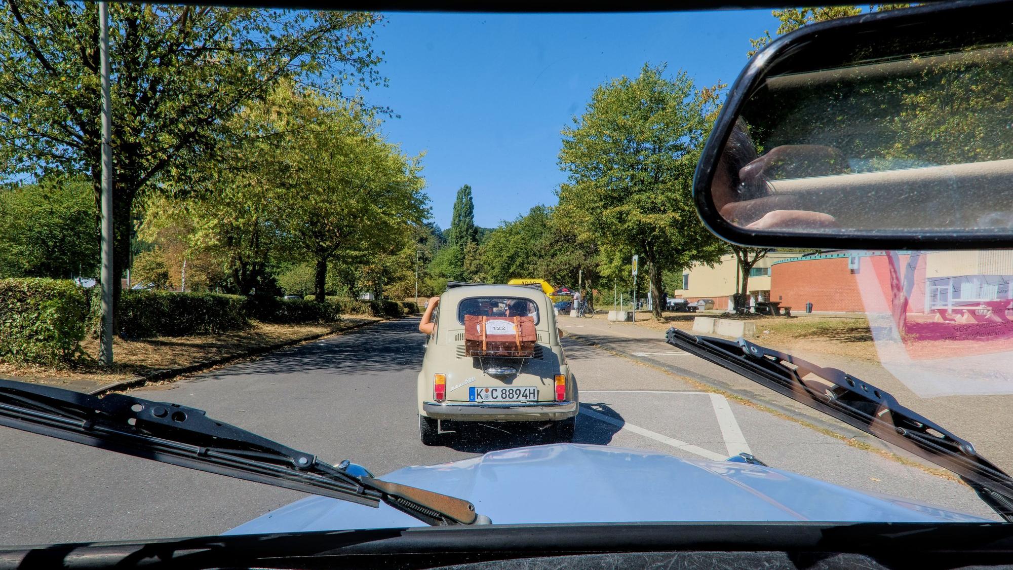 Ein Auto fährt vor einer blauen Ente.