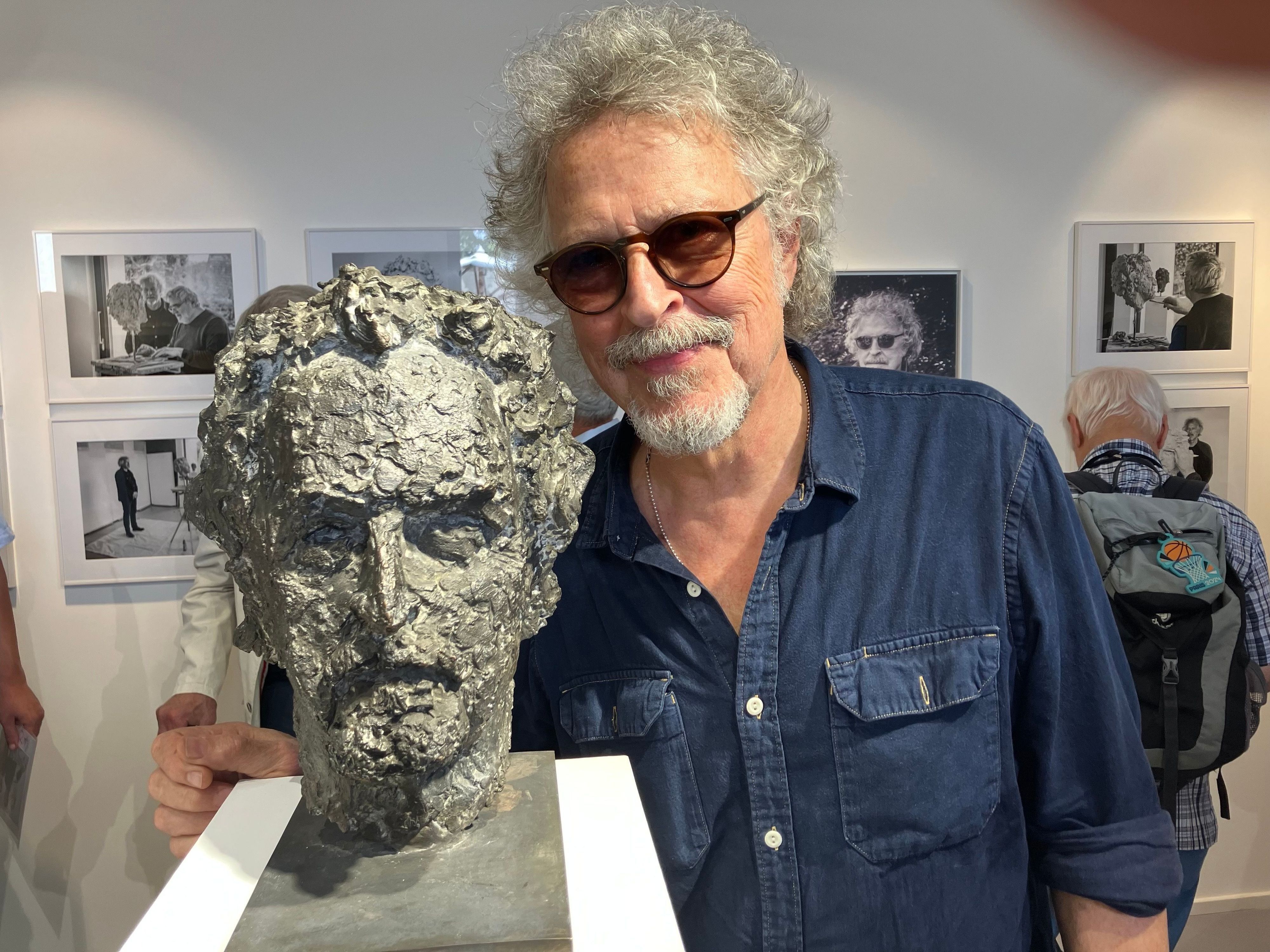 Wolfgang Niedecken steht bei der Eröffnung einer Vernissage  neben seinem Bronze-Kopf.