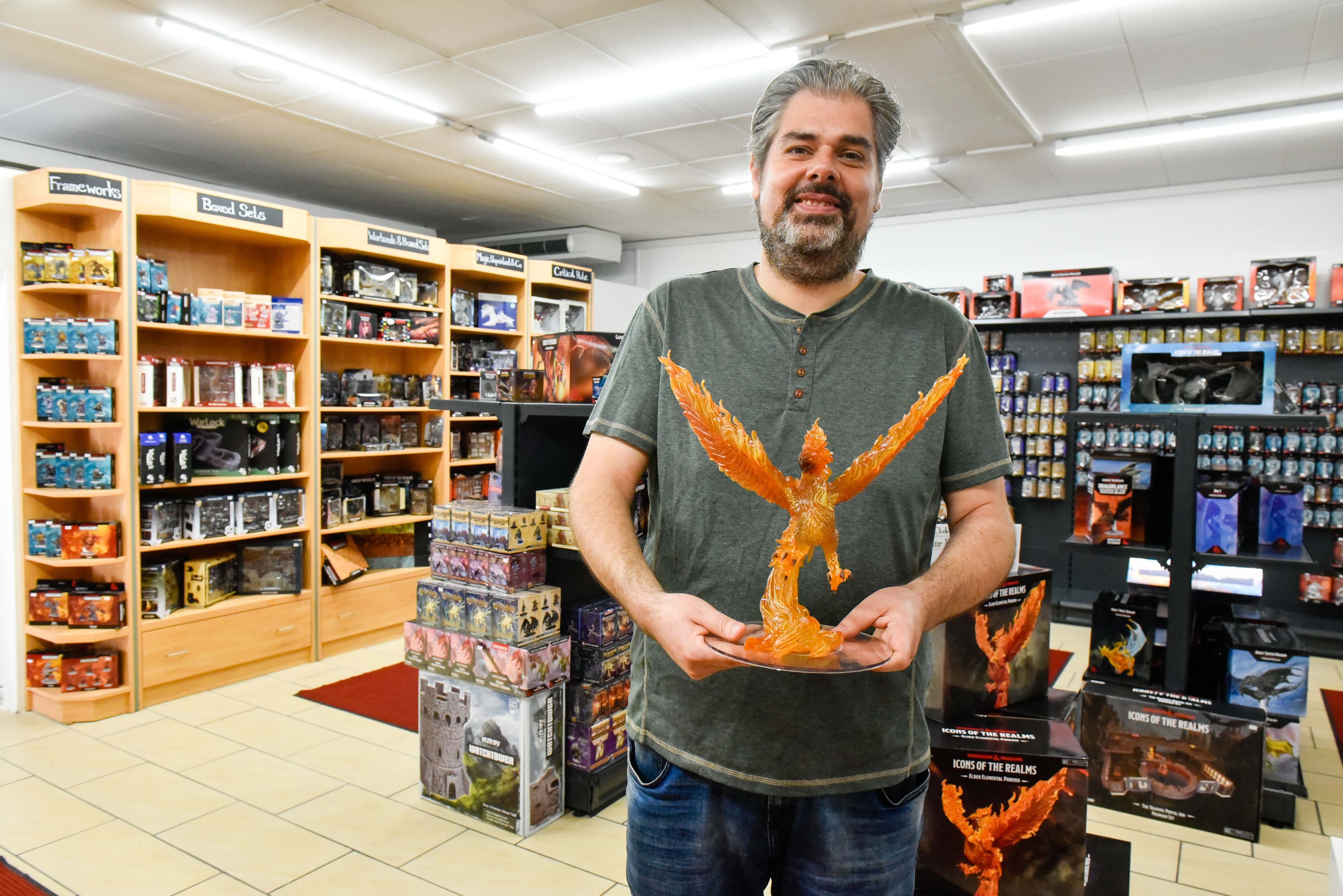 Das Foto zeigt einen Mann, der eine Drachenfigur in den Händen hält.