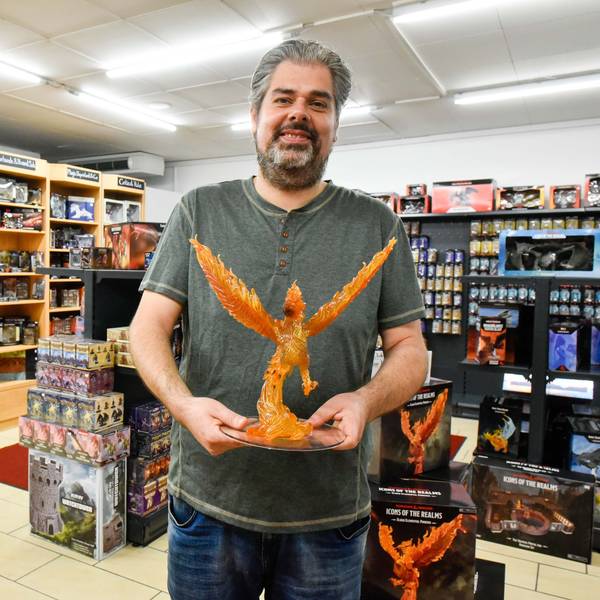 Das Foto zeigt einen Mann, der eine Drachenfigur in den Händen hält.