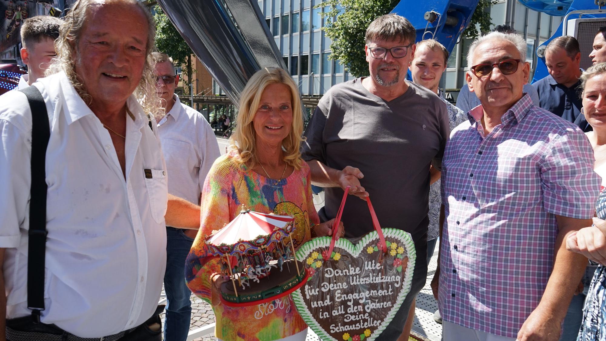 Ute Unrau steht mit ihrem Mann Burkhardt und Schaustellern auf einem Kirmesgeschäft der Laurentiuskirmes 2026 und wird verabschiedet.
