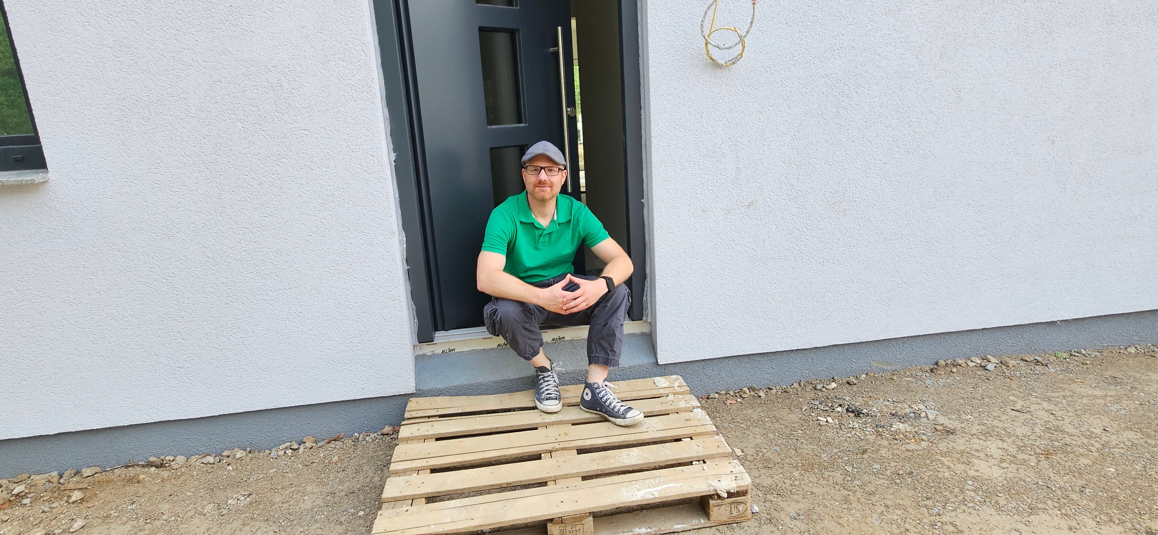 Das Bild zeigt Lars Ollig sitzend vor seinem Haus.