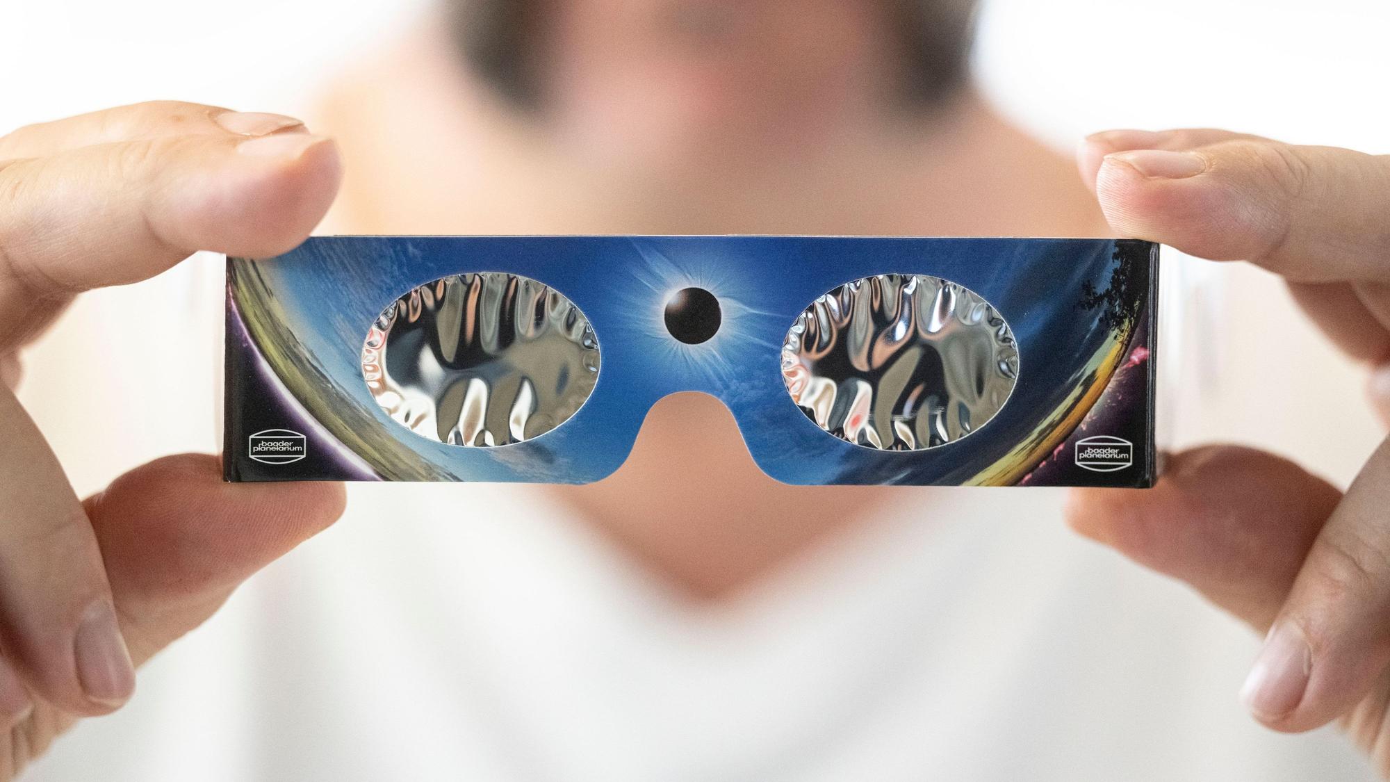 Ein Angestellter hält in einem Fotofachhandelsgeschäft eine Sonnenfinsternis-Brille in der Hand.