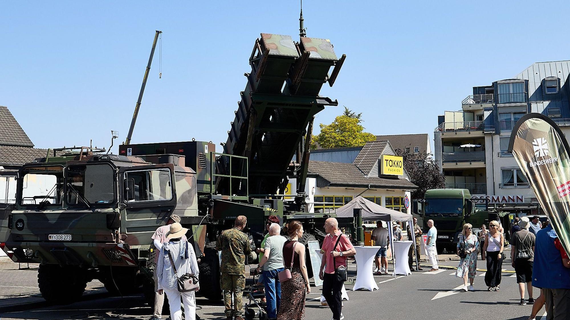 Menschen schlendern an dem MAN-Fahrzeug mit dem Patriot-Waffensystem vorbei.