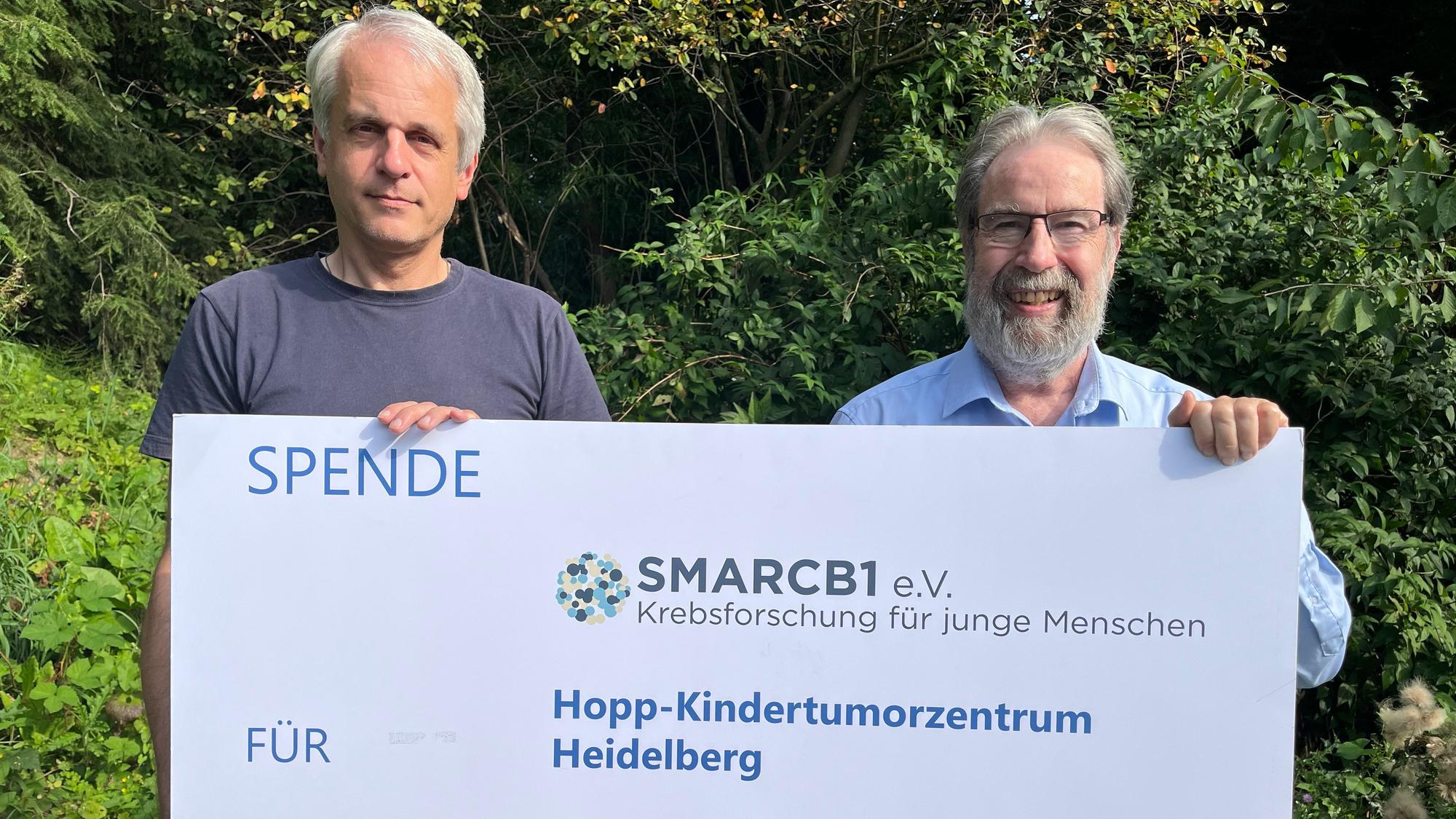 Zwei Männer halten einen Spendenscheck in der Hand.